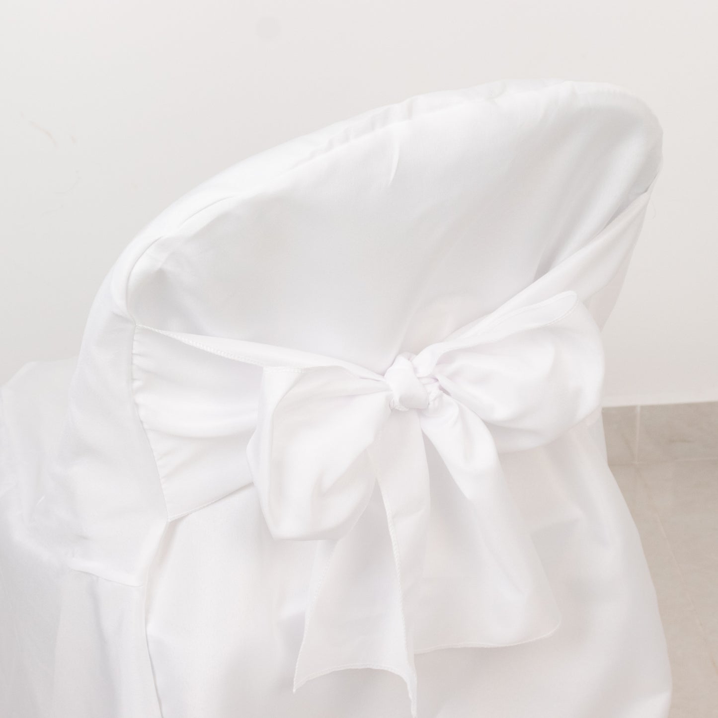 White polyester slip-on folding chair cover with attached sash.