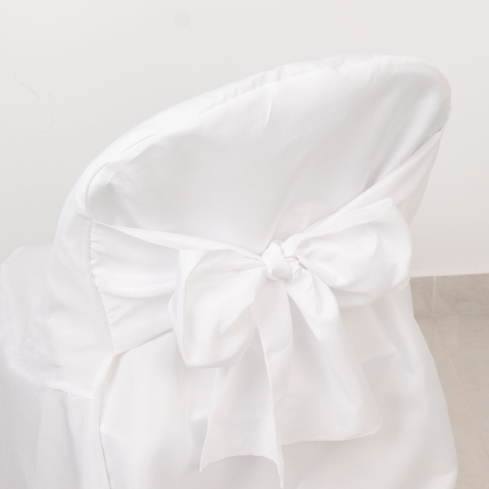 White polyester slip-on folding chair cover with attached sash.