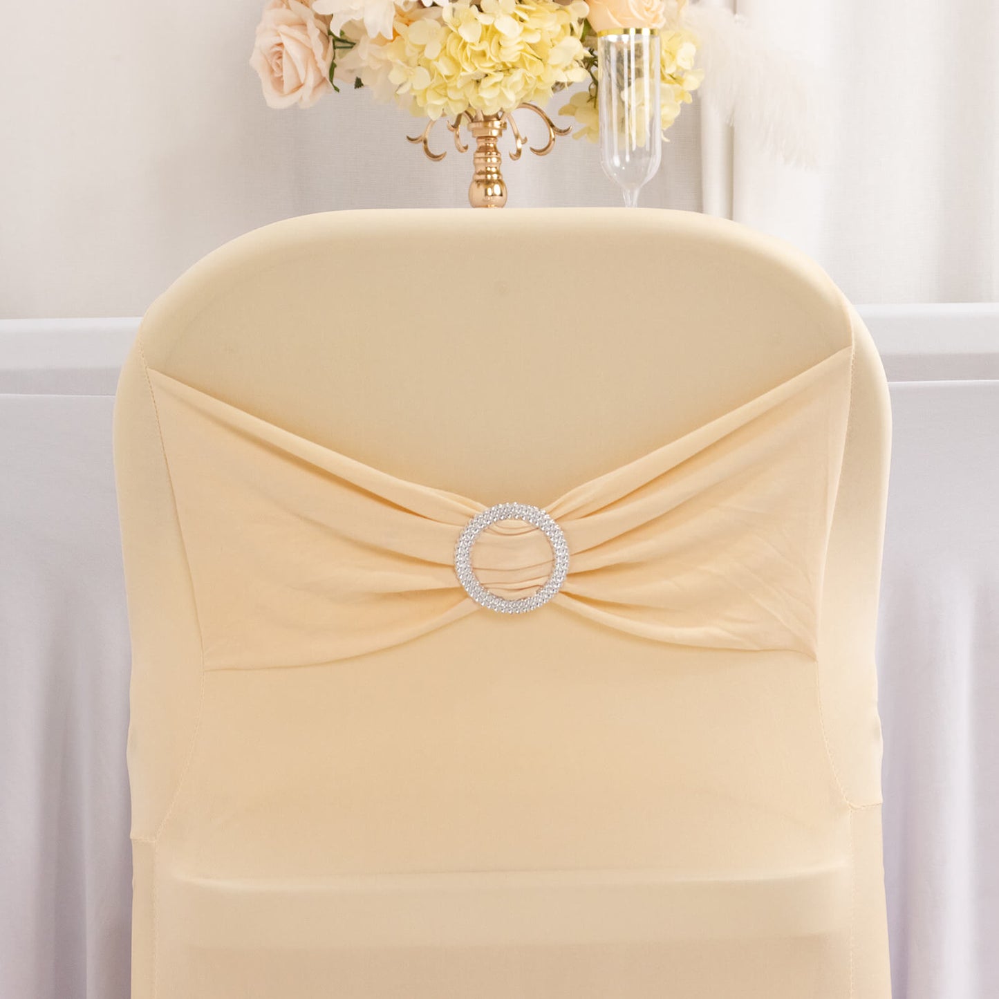 Beige spandex chair cover with silver rhinestone buckle.