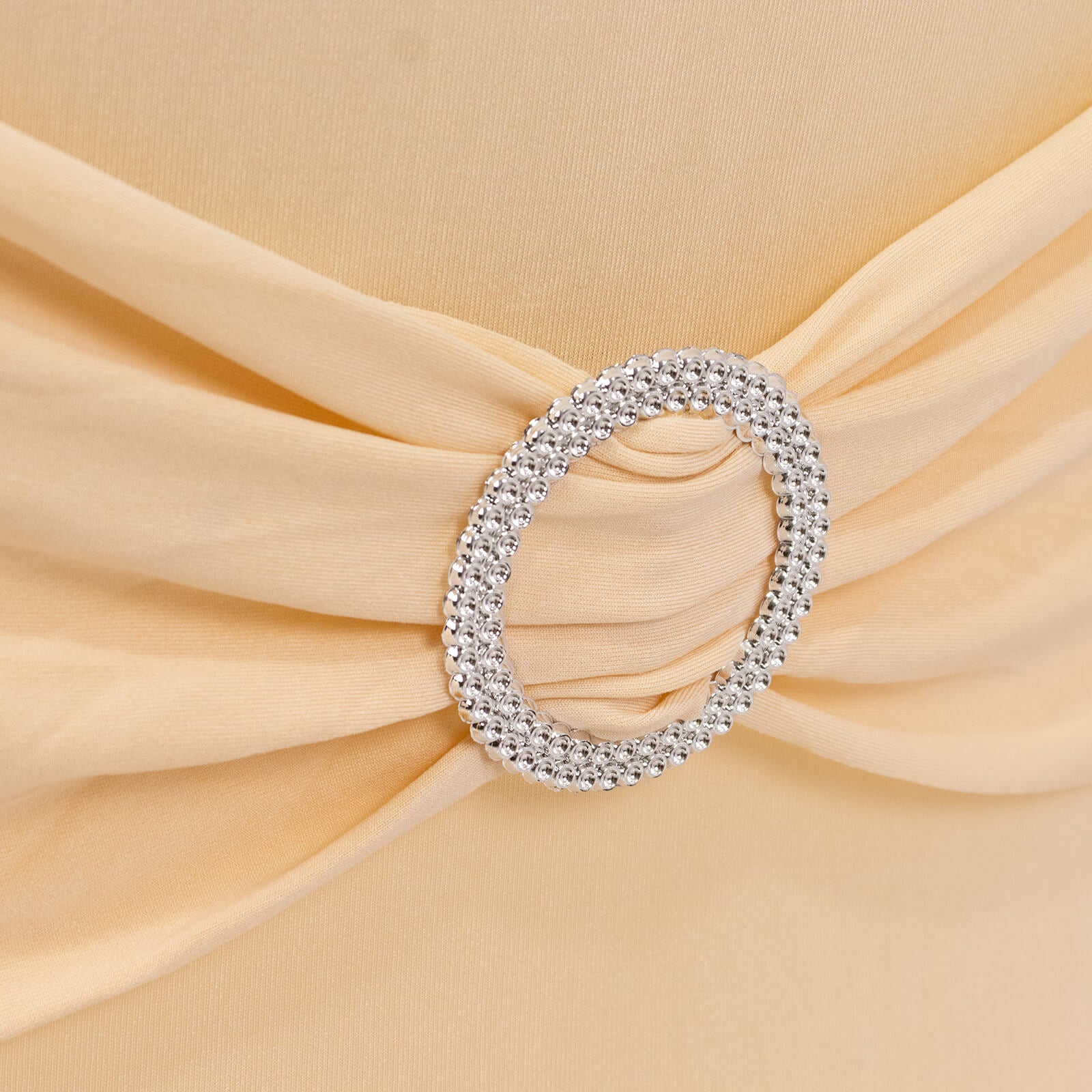 Beige spandex folding chair cover with silver rhinestone buckle.