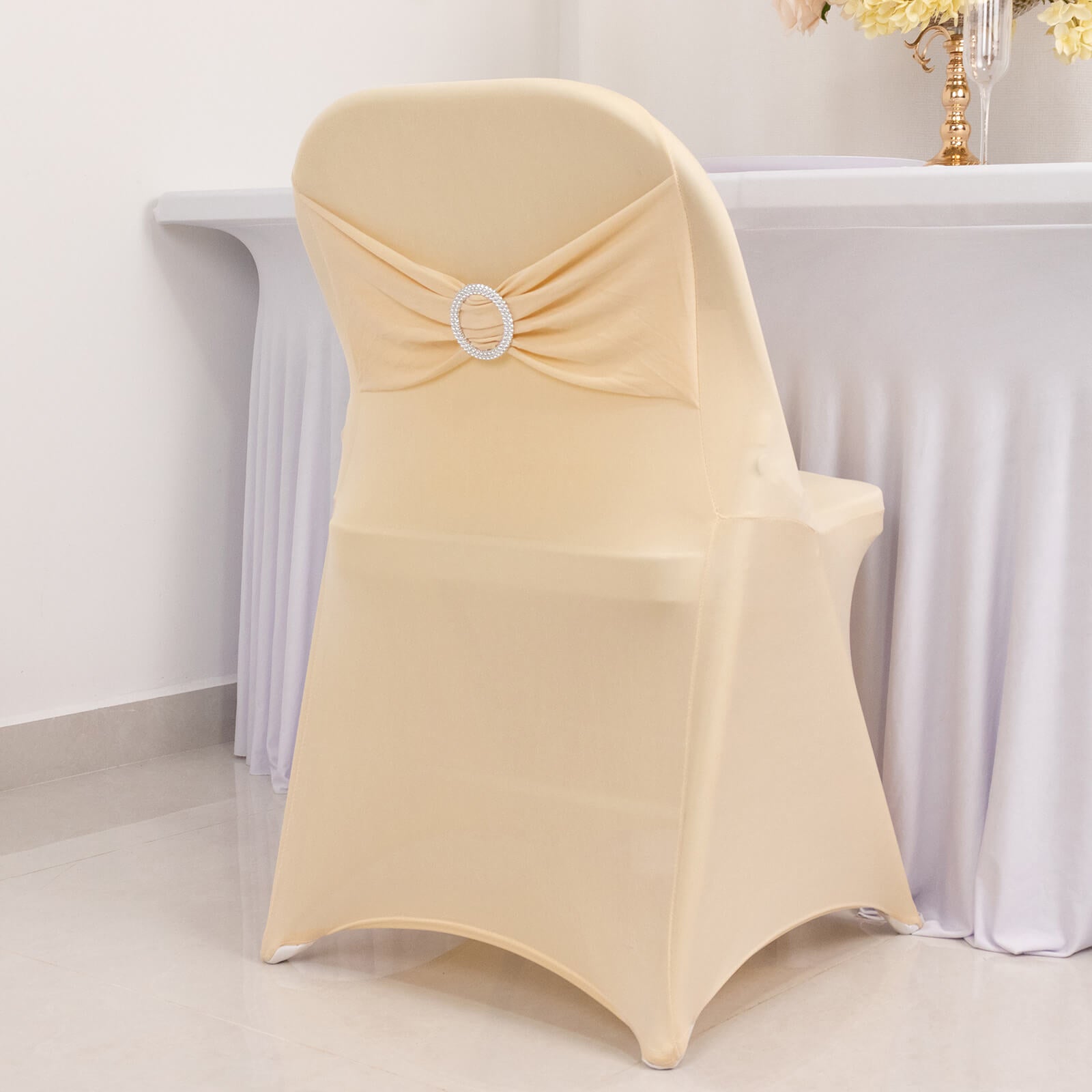 Beige spandex folding chair cover with silver rhinestone sash.