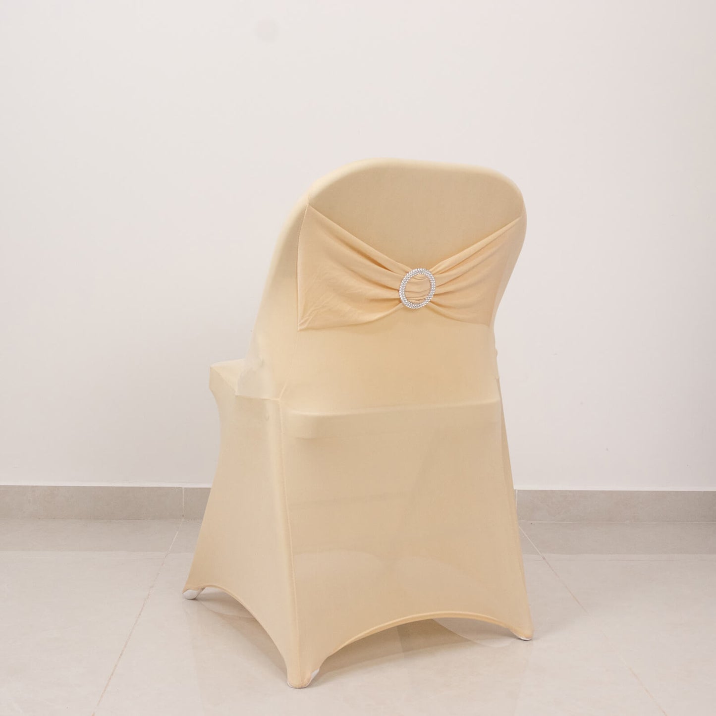 Beige spandex chair cover with silver rhinestone sash.