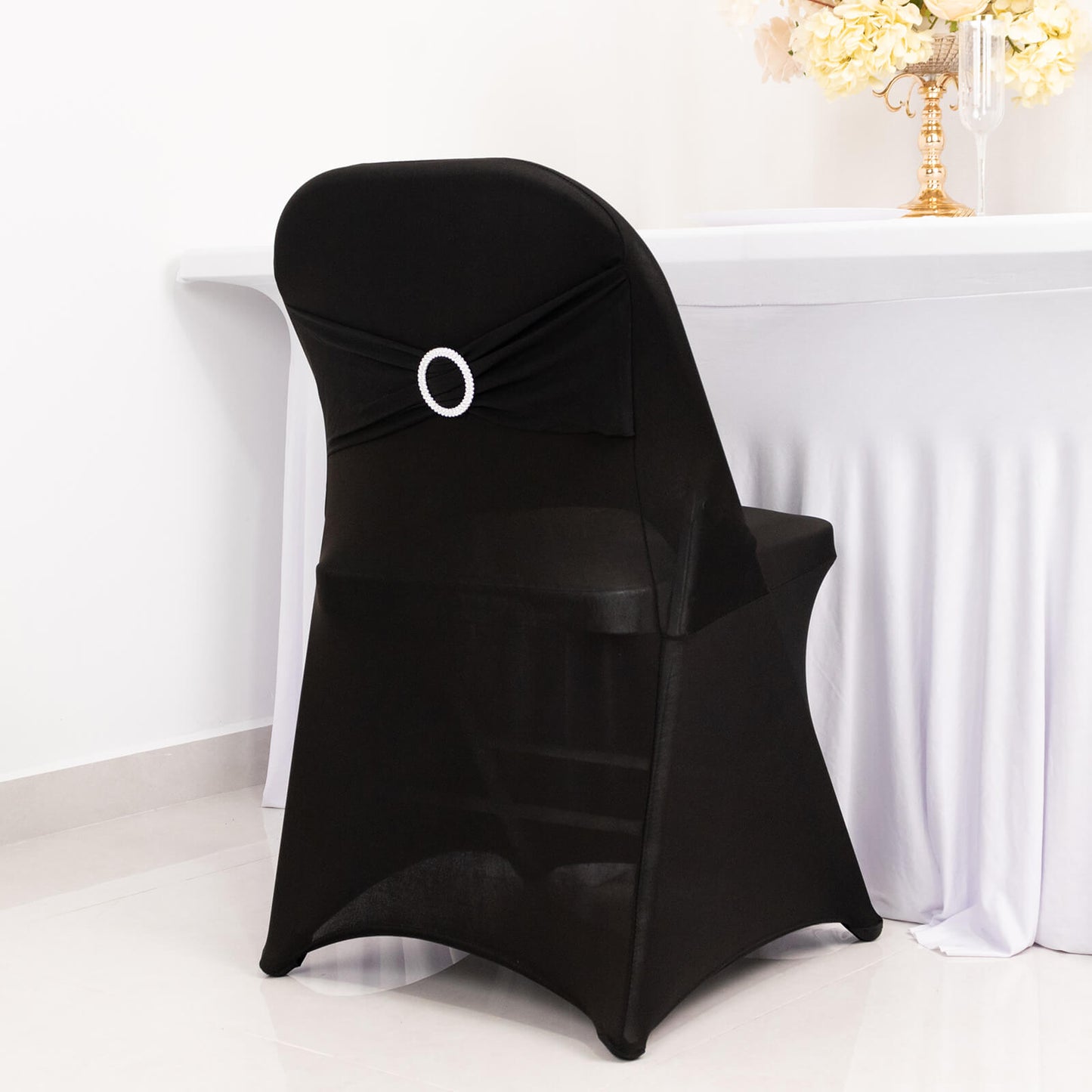 Black spandex folding chair cover with silver rhinestone sash.