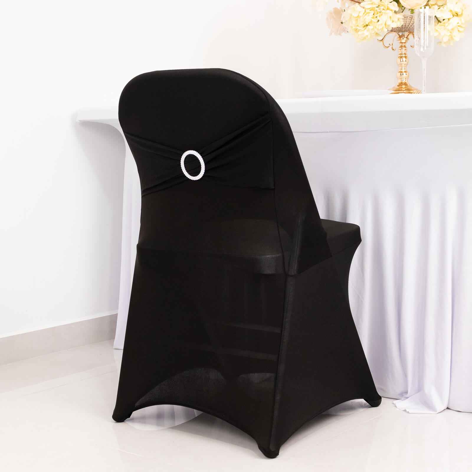Black spandex folding chair cover with silver rhinestone sash.