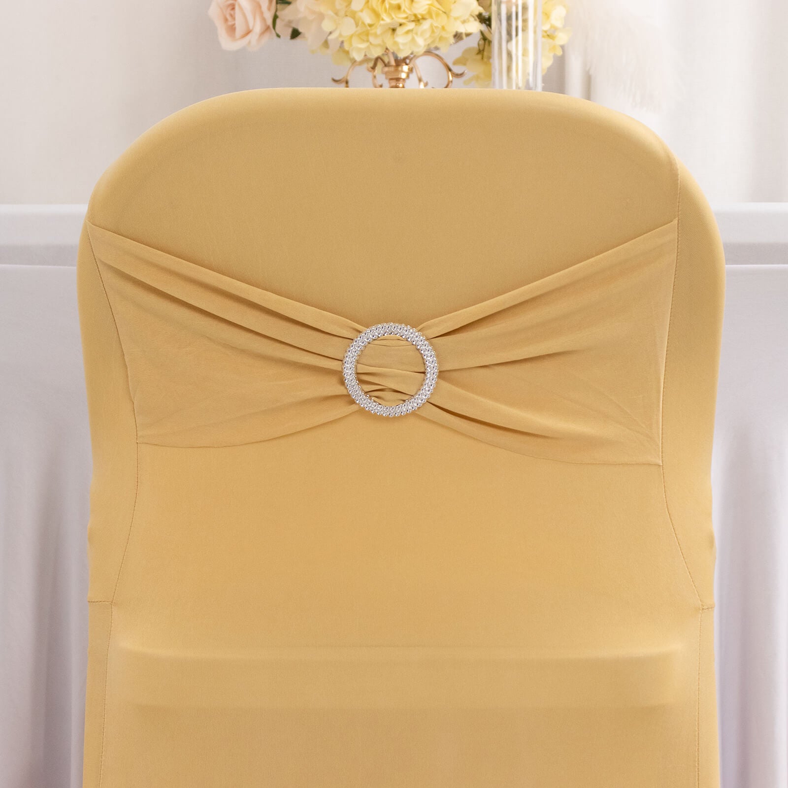 Champagne folding chair cover with silver rhinestone sash.