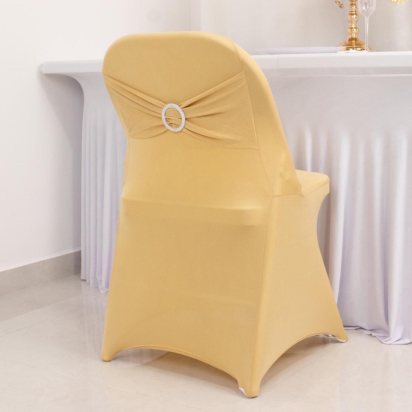 Champagne folding chair cover with rhinestone buckle sash.