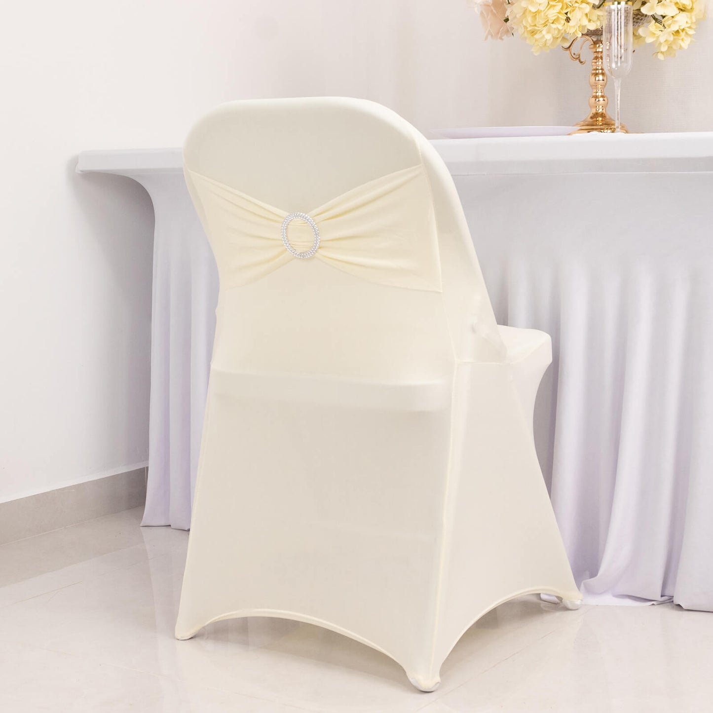 Ivory spandex folding chair cover with silver rhinestone sash.