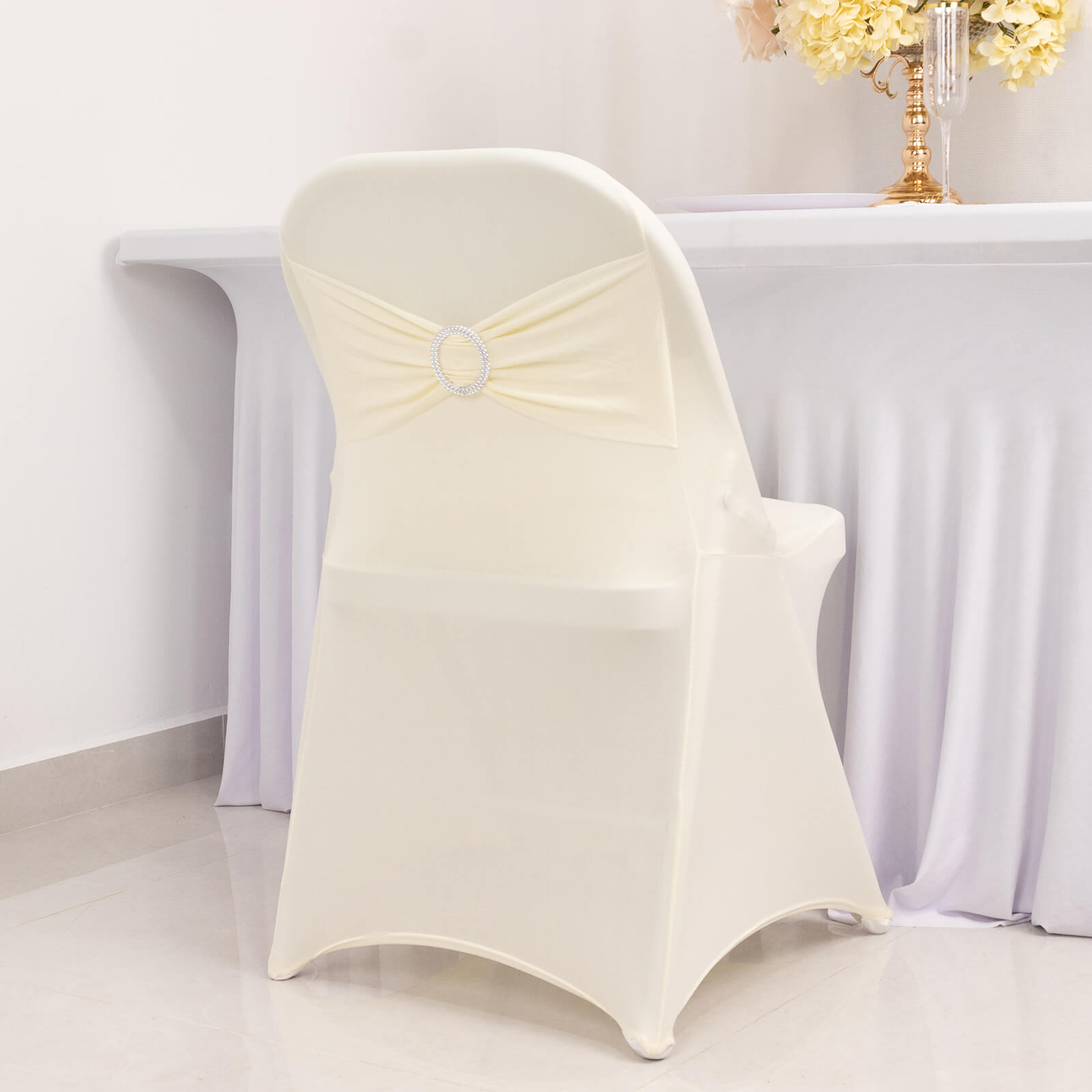 Ivory spandex folding chair cover with silver rhinestone sash.