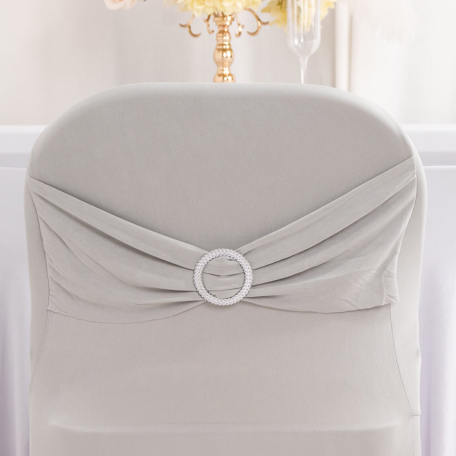Silver spandex chair cover with rhinestone buckle detail.