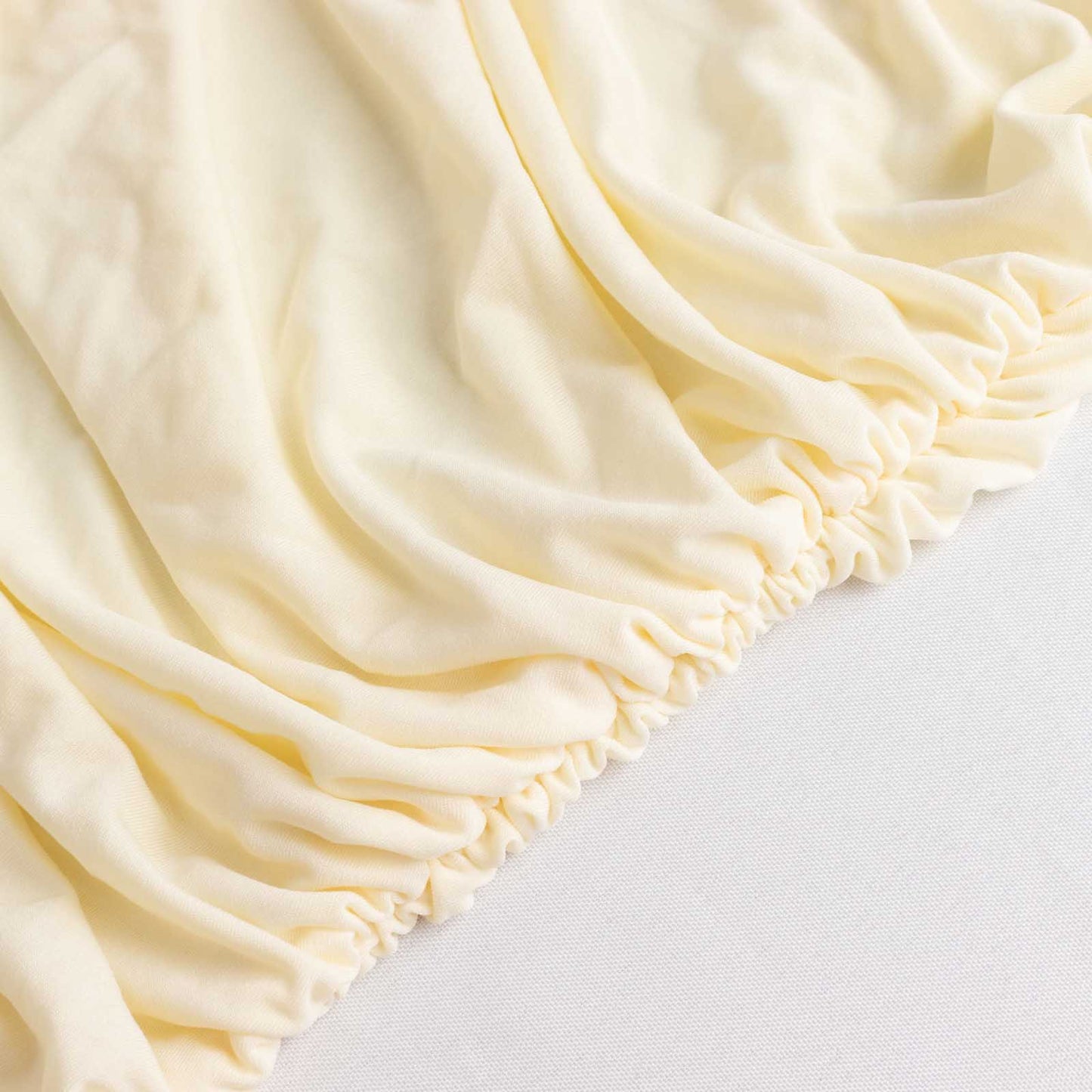 Ivory fitted spandex banquet chair cover with gathered edges.