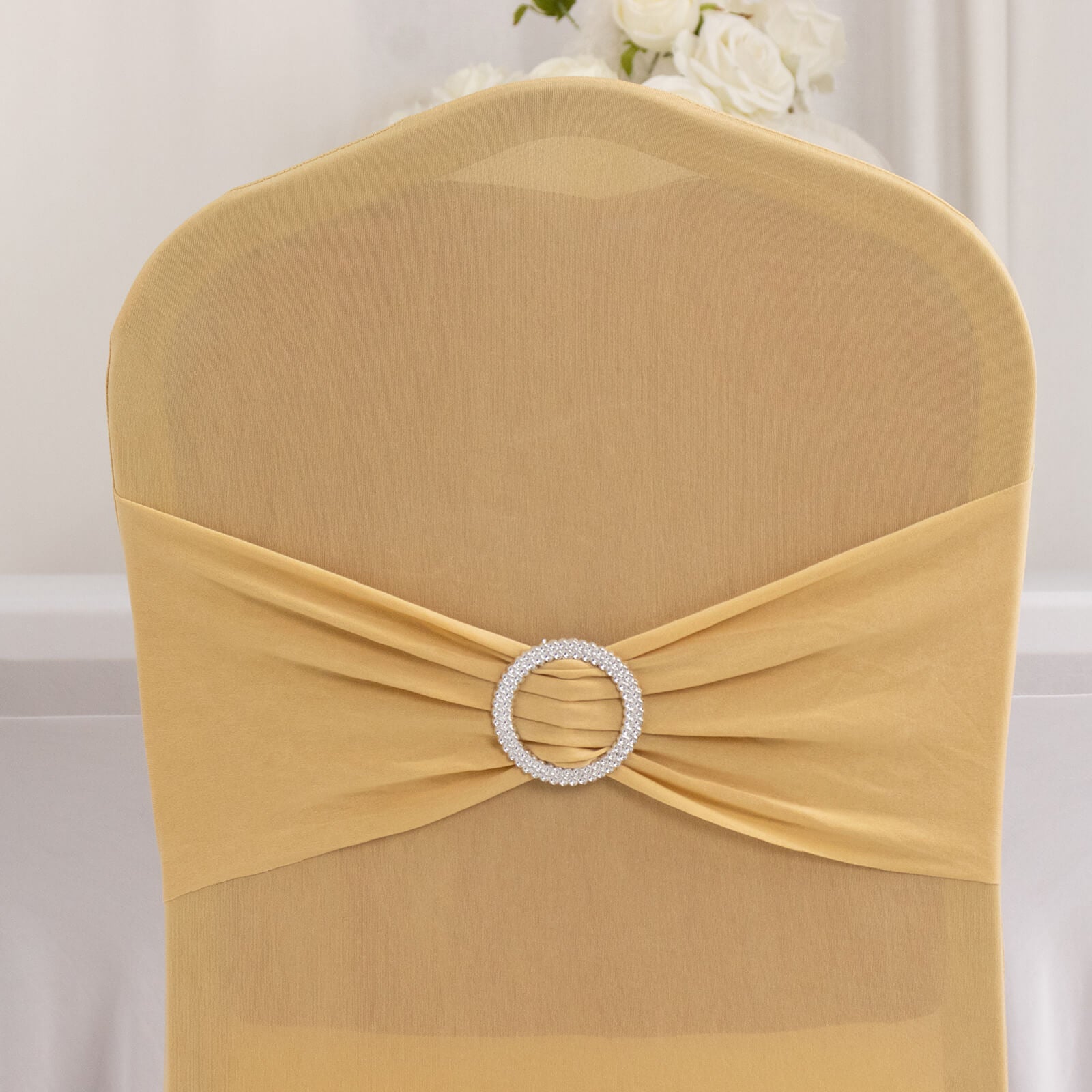 Champagne chair cover with silver rhinestone buckle on a fitted chair.