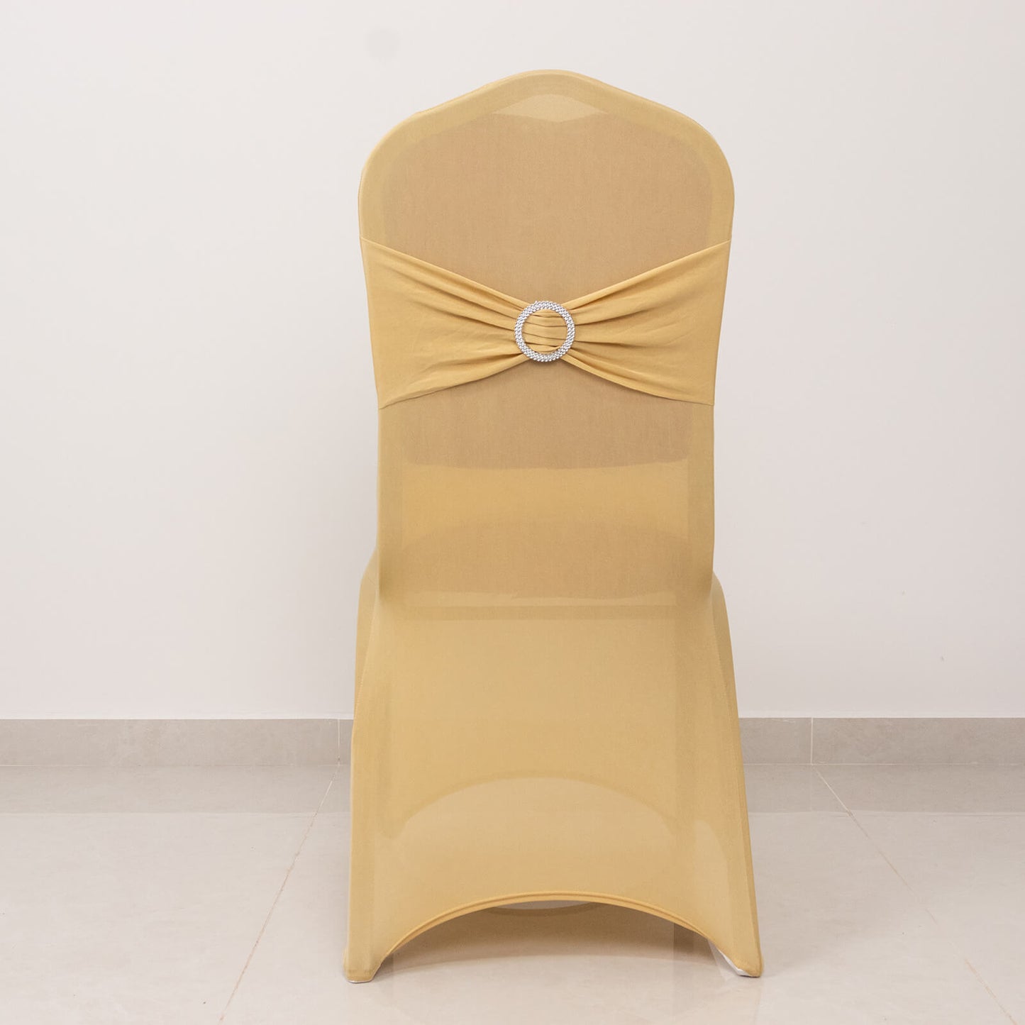 Champagne chair cover with silver rhinestone sash for elegant events.