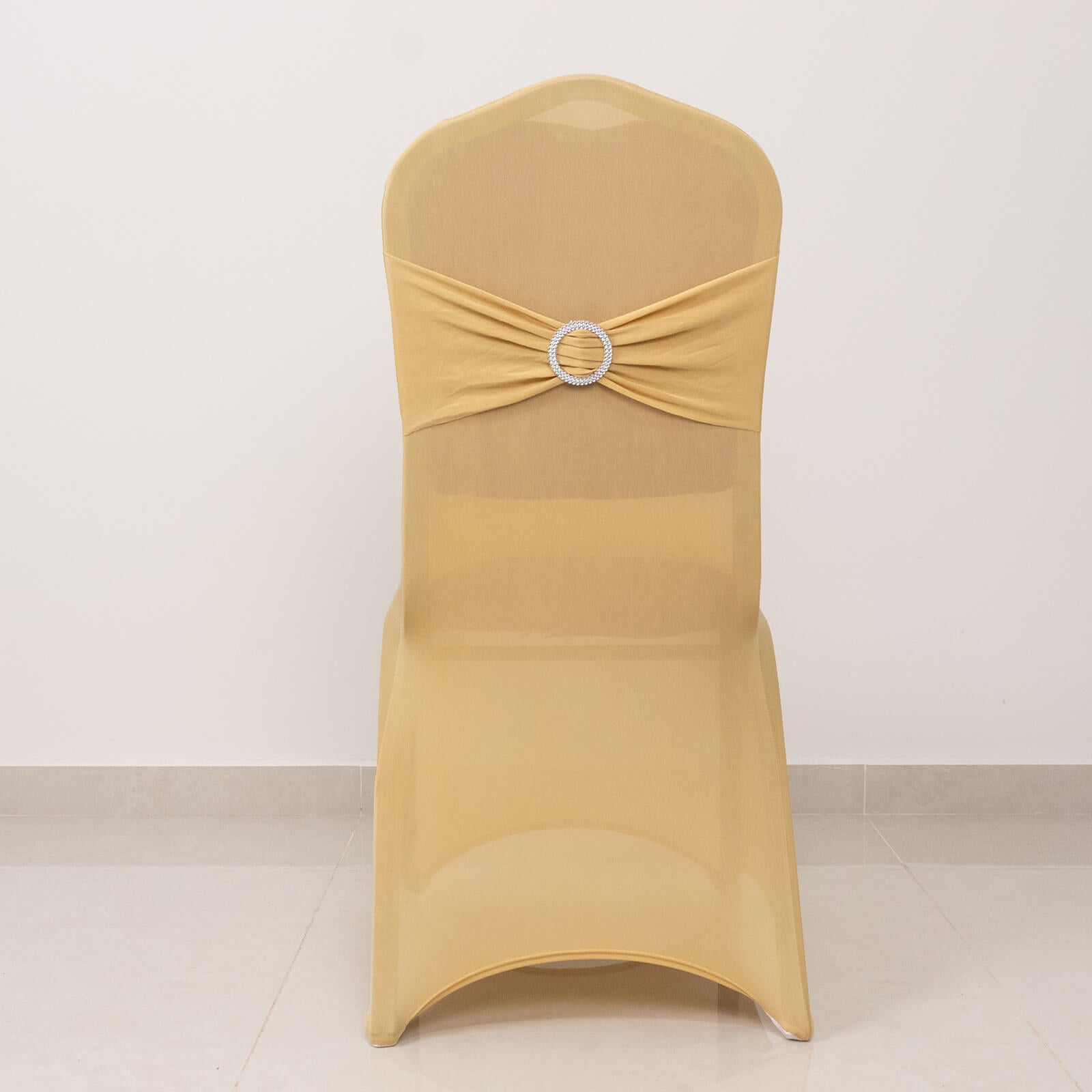 Champagne chair cover with silver rhinestone sash for elegant events.