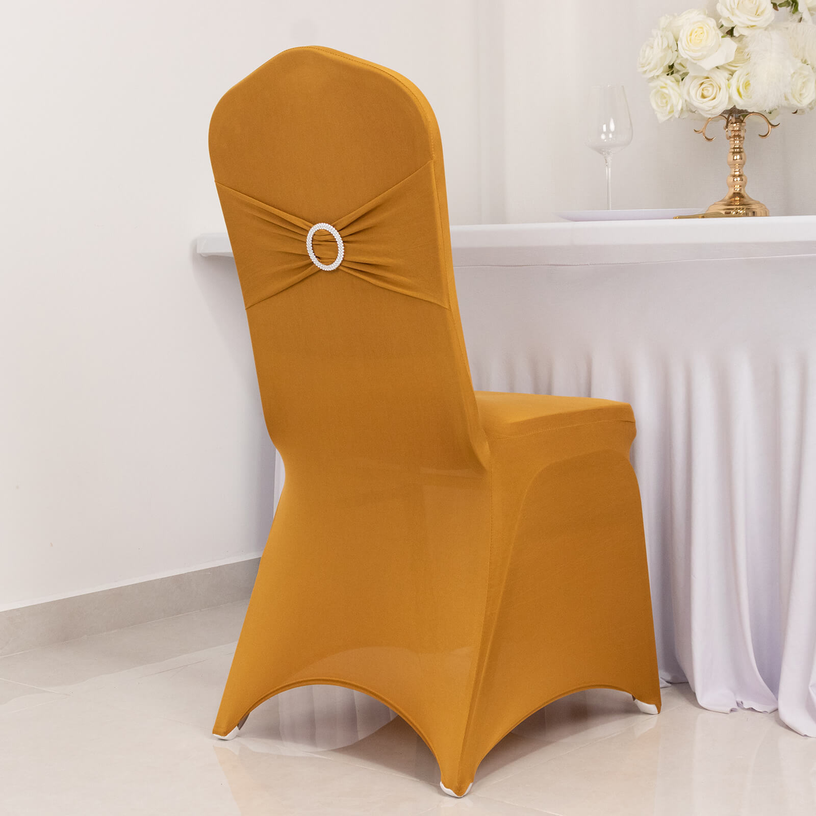 Gold spandex banquet chair cover with rhinestone buckle detail.