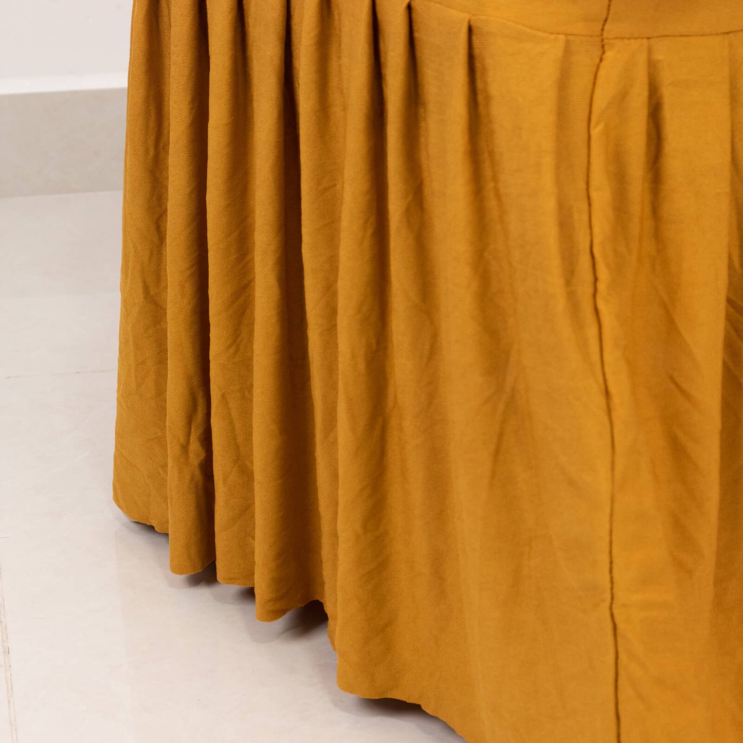 Gold pleated skirt banquet chair slipcover in a warm golden hue.