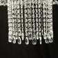 Clear acrylic crystal chandelier cake stand with hanging bead chains.