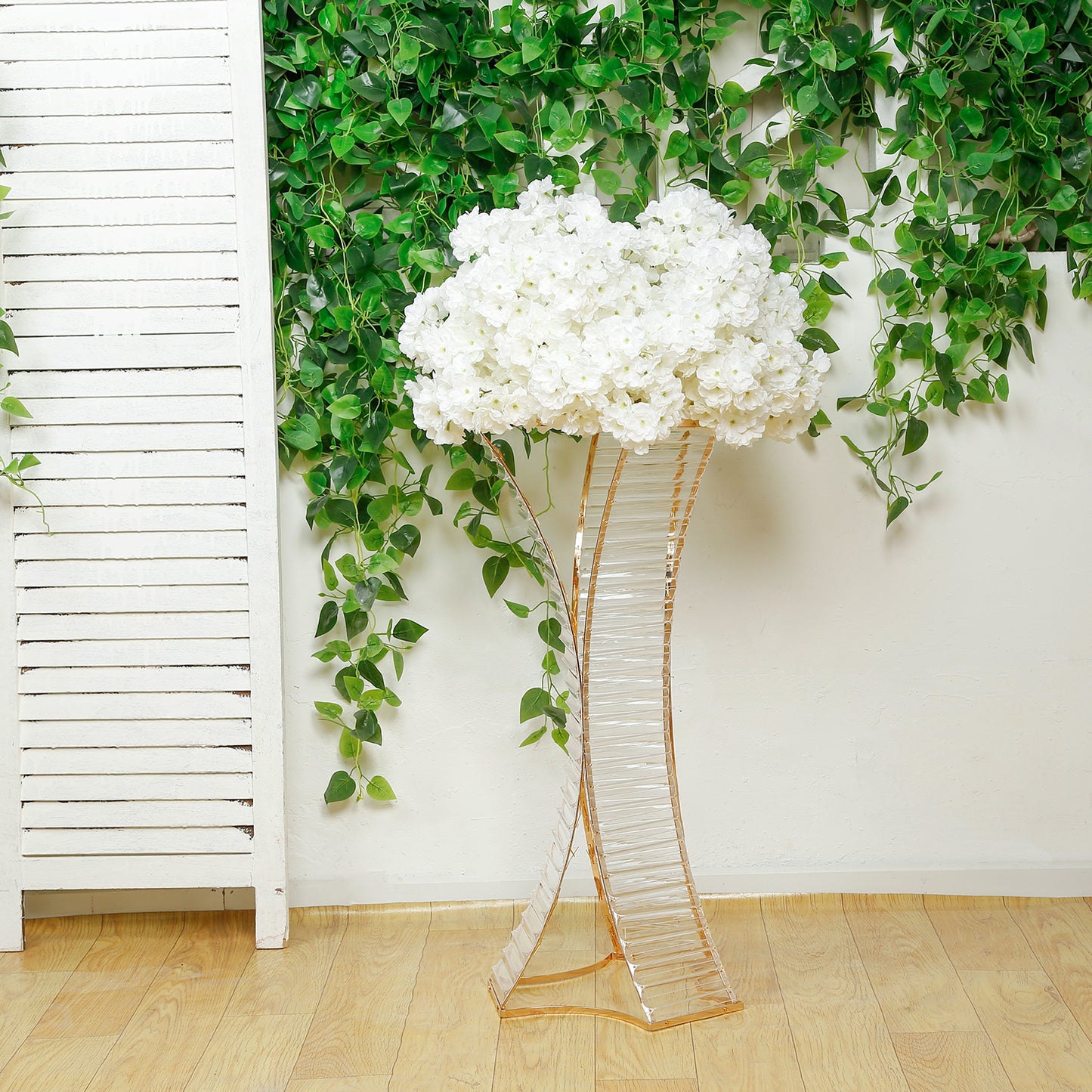 White flower stand with crystal pendant and gold metal frame.