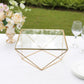 Gold metal geometric cake stand display with square glass top.