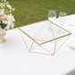Gold geometric cake stand with square glass top on a table.