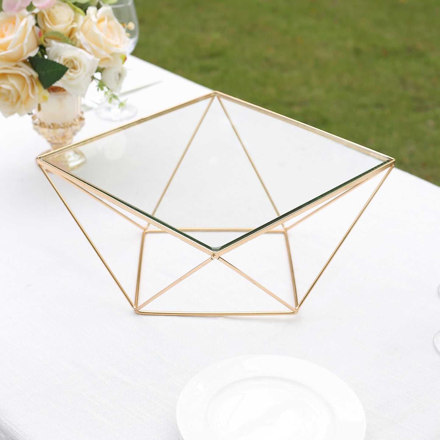 Gold geometric cake stand with square glass top, perfect for displays.