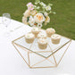 Gold metal geometric cake stand with glass top displaying cupcakes.
