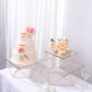 Gold metal geometric stackable cake stands with glass tops.