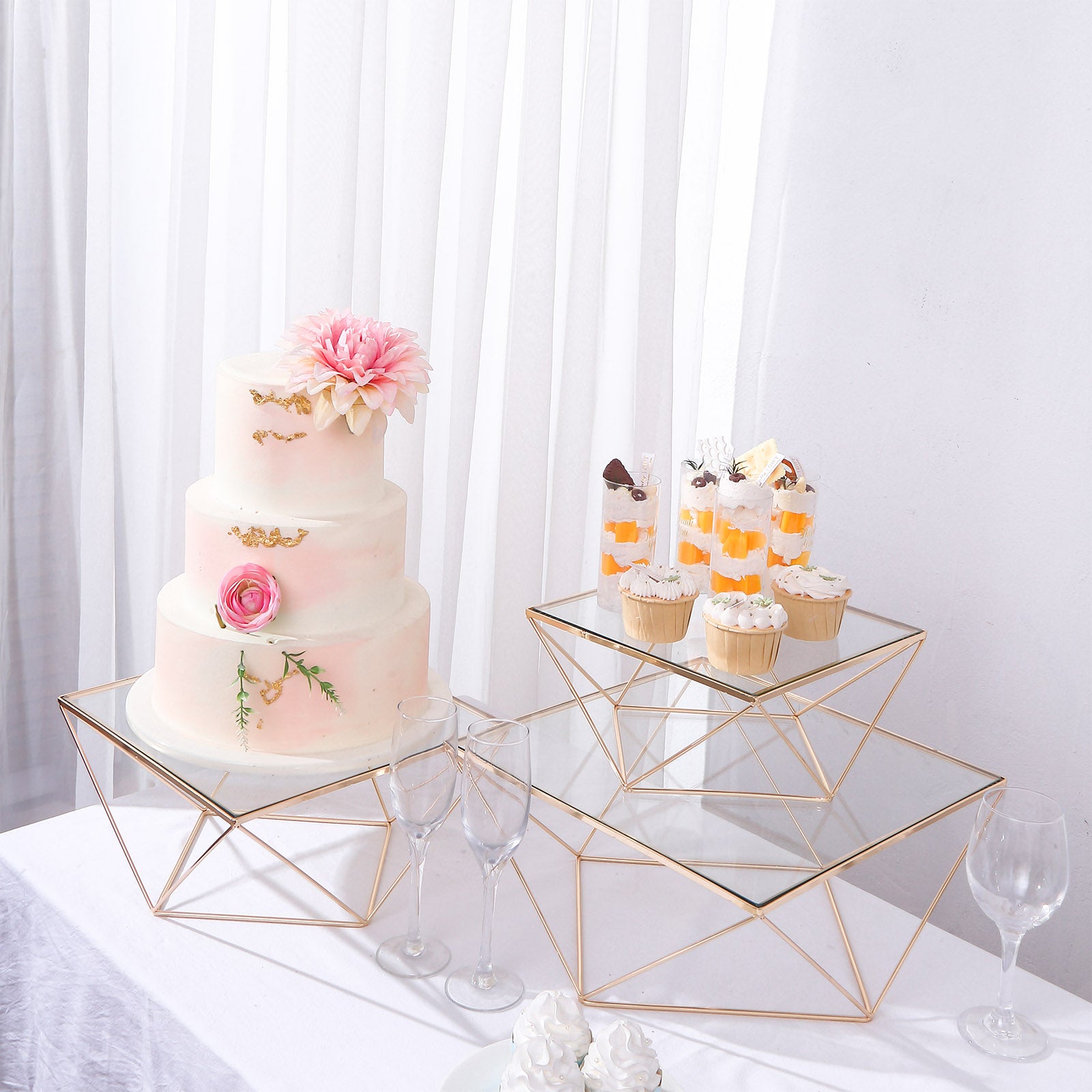 Gold metal geometric stackable cake stands with glass tops.