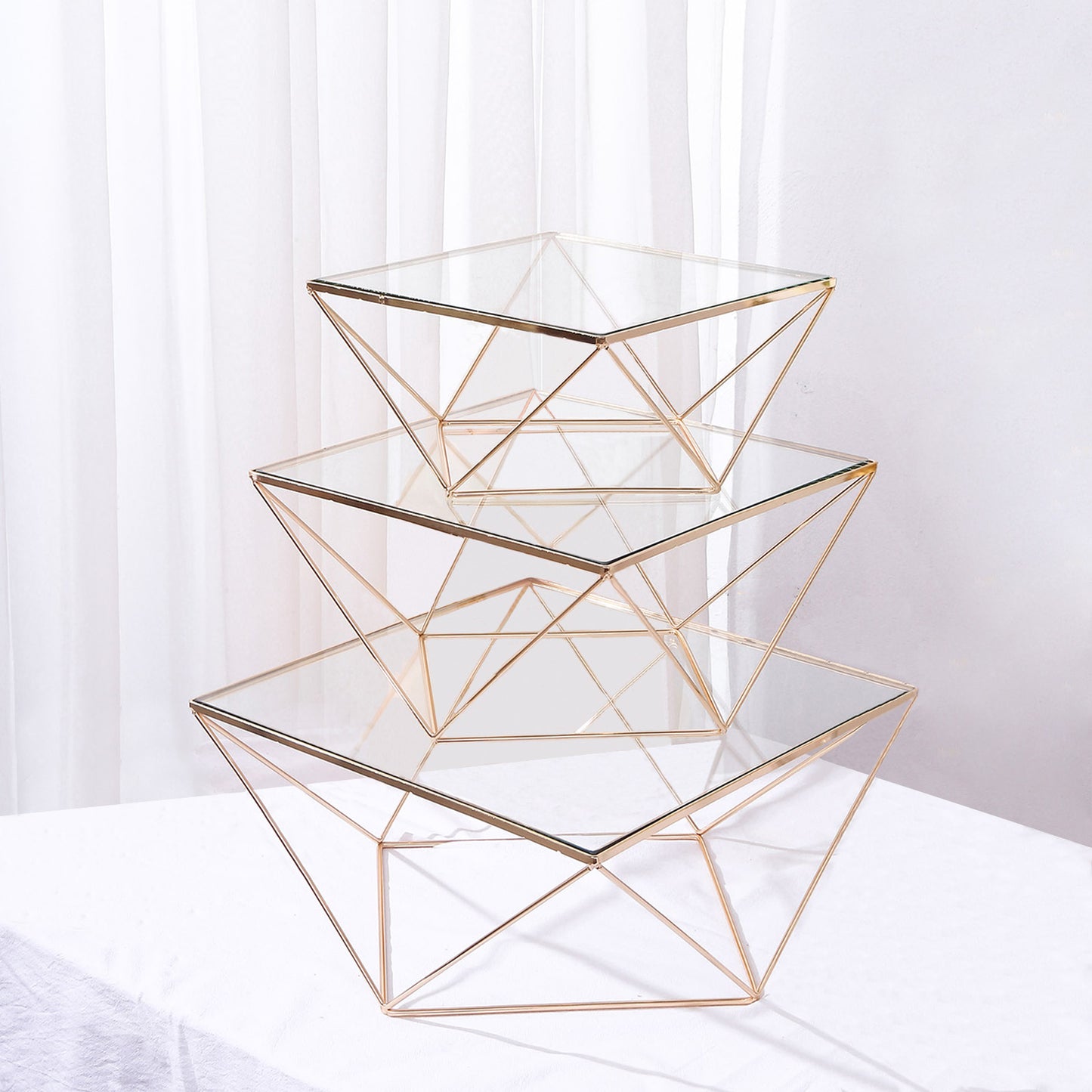 Gold metal geometric stackable cake stands with glass tops.