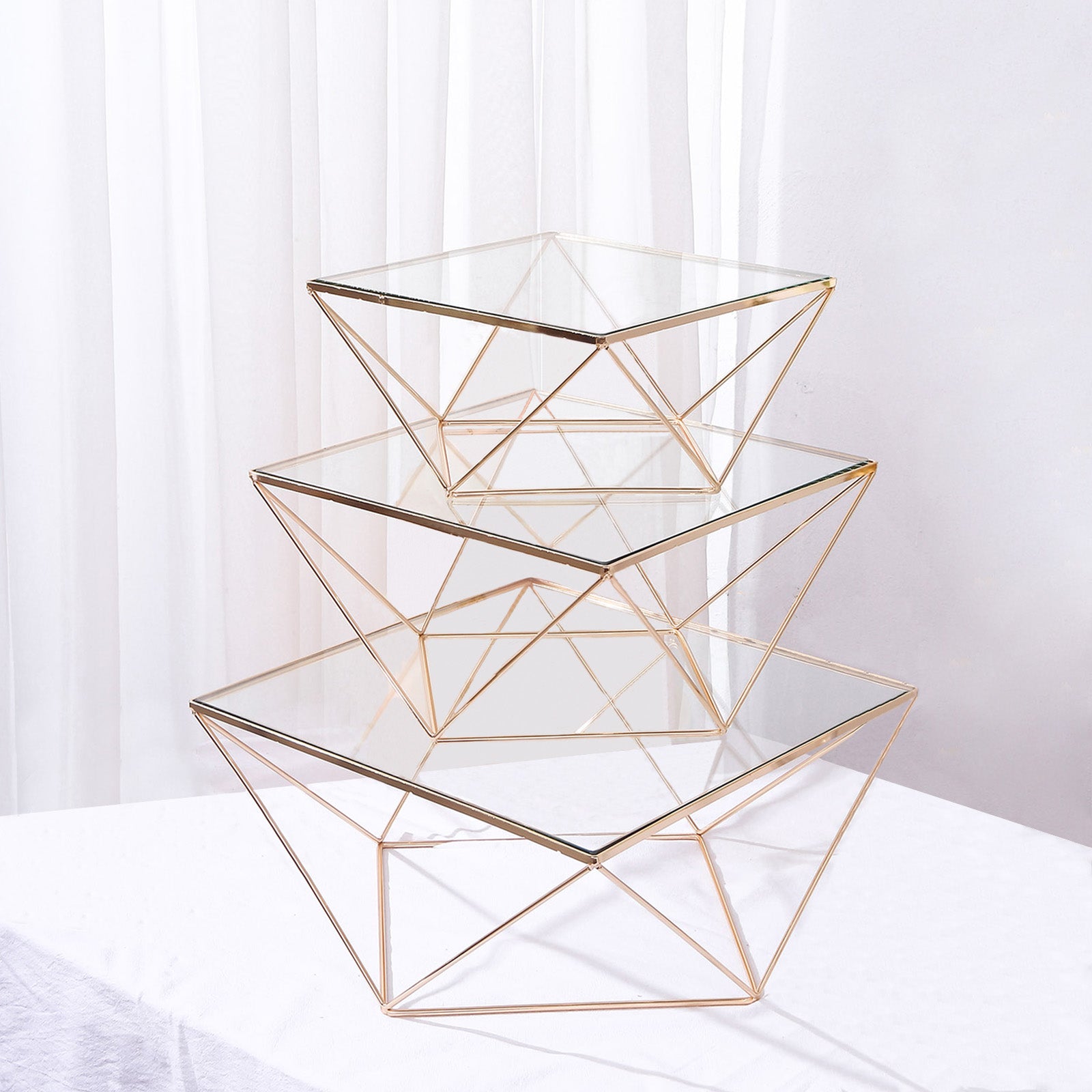 Gold metal geometric stackable cake stands with glass tops.