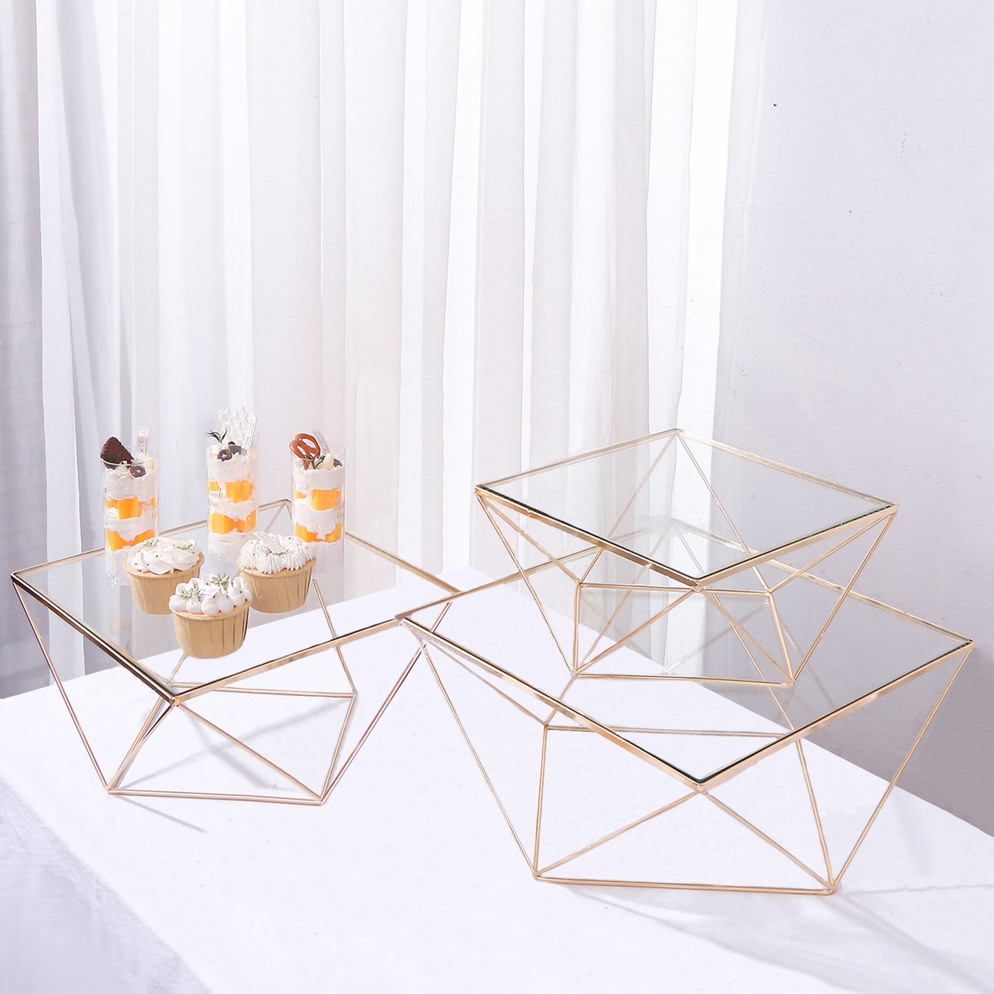 Gold metal geometric stackable cake dessert stands with glass tops.