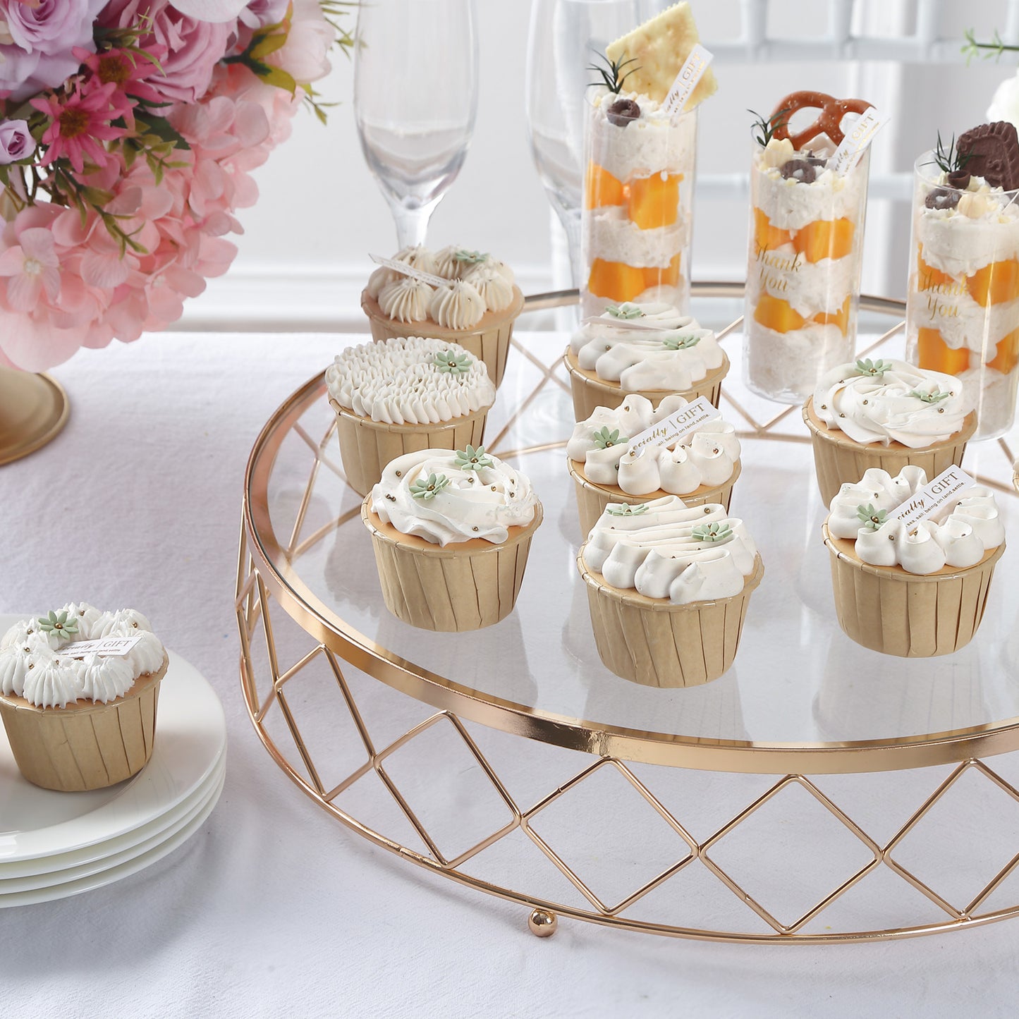 Gold geometric diamond cut cake stand with glass top displaying cupcakes.