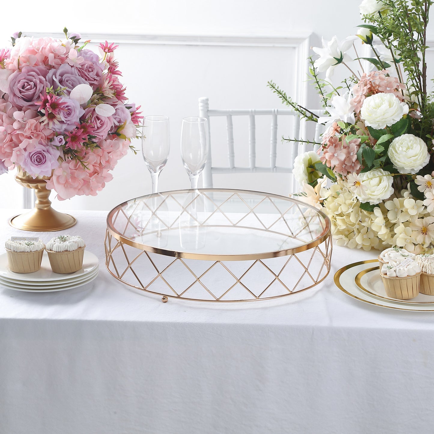 Gold geometric diamond cut cake stand with glass top on a white table.