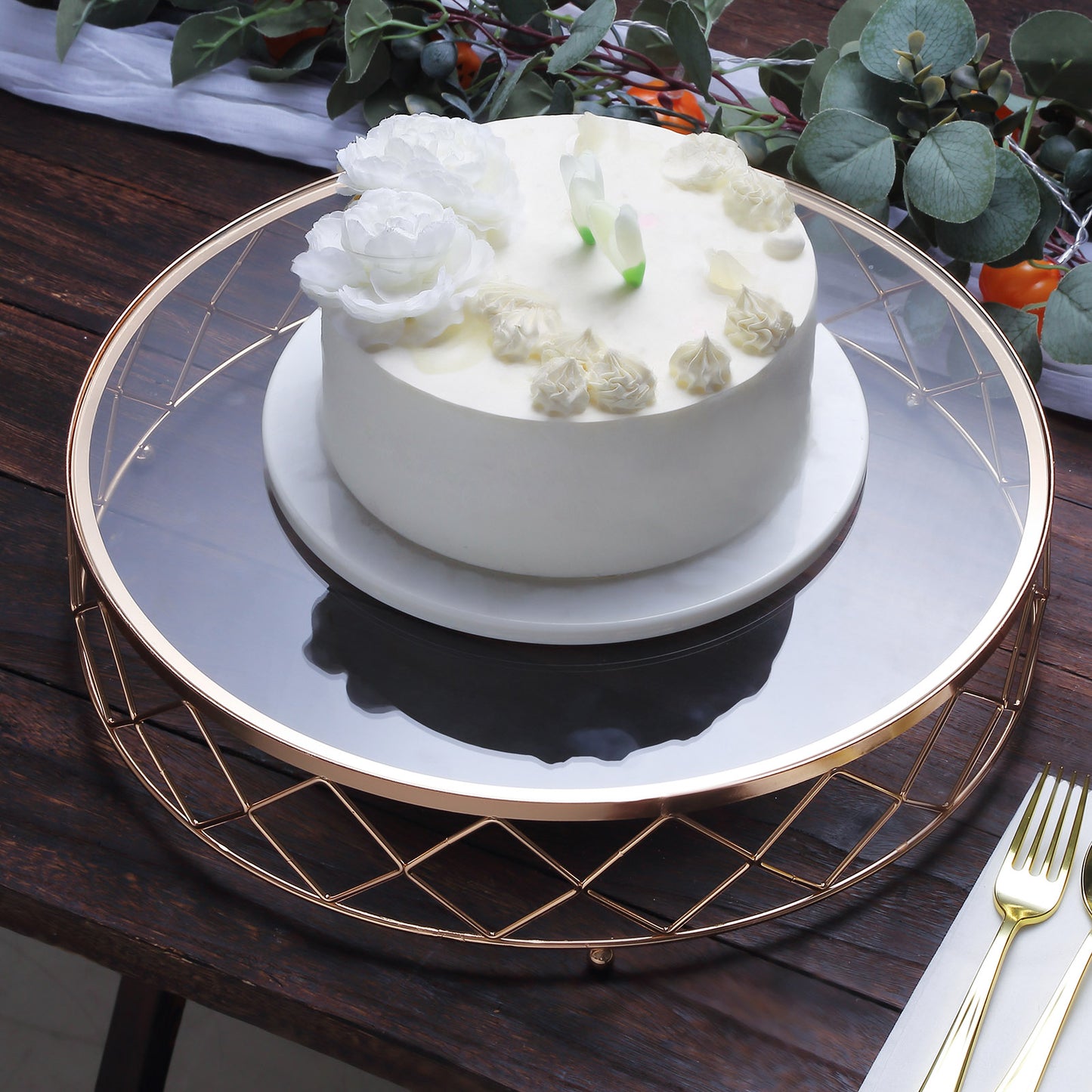 Gold geometric diamond cut cake stand with glass top displaying a white cake.