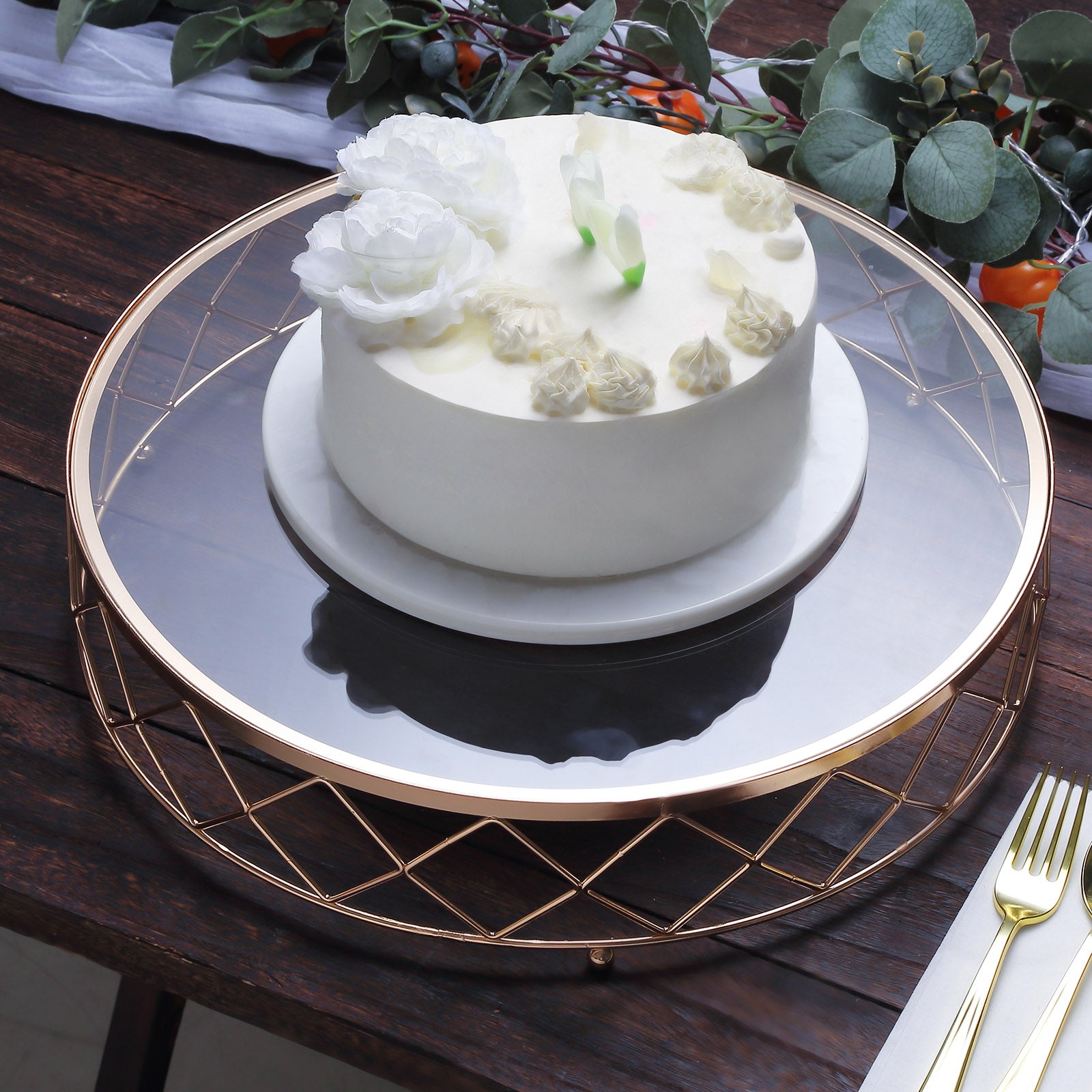 Gold geometric diamond cut cake stand with glass top displaying a white cake.