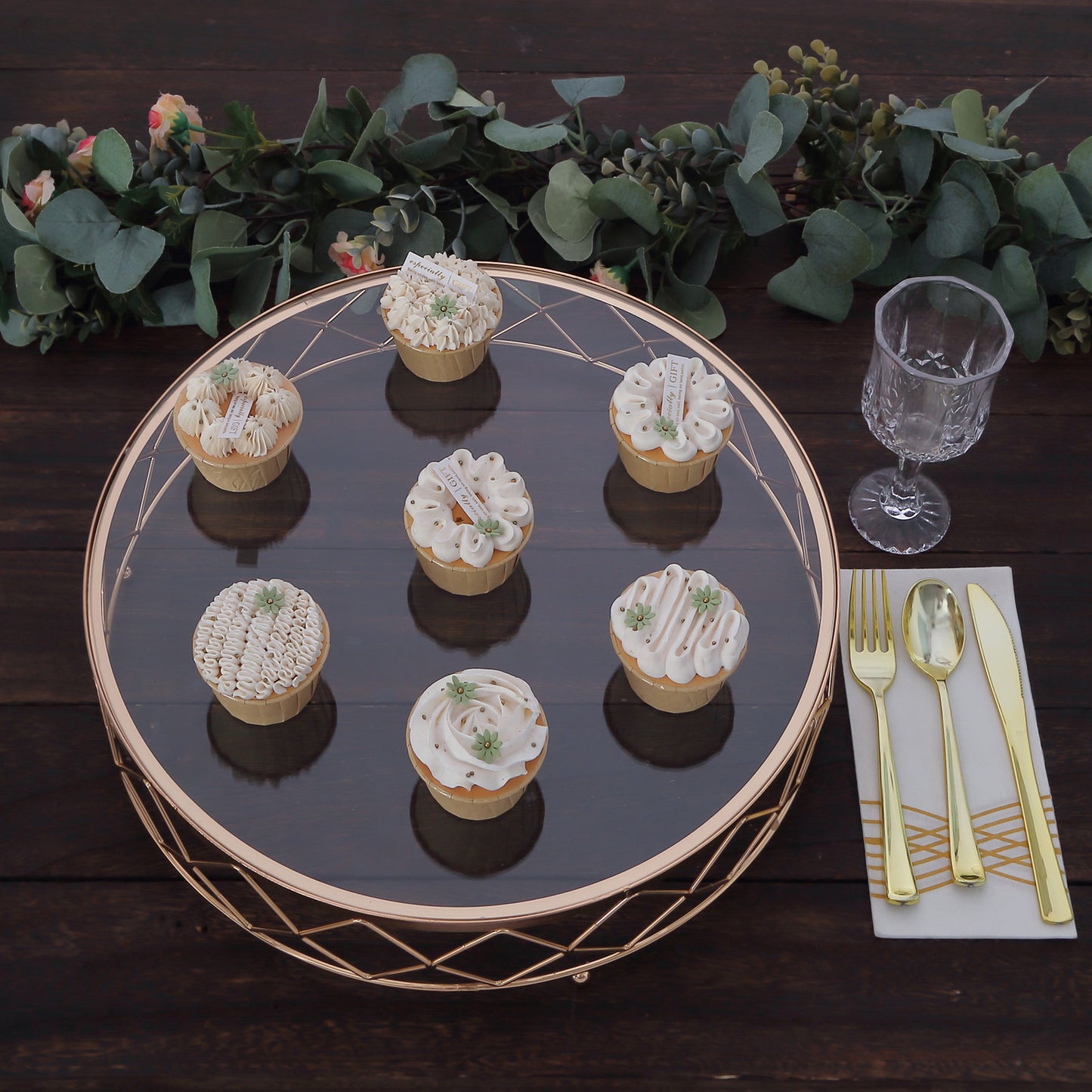 Gold geometric diamond cut cake stand with glass top, displaying delicious cupcakes.