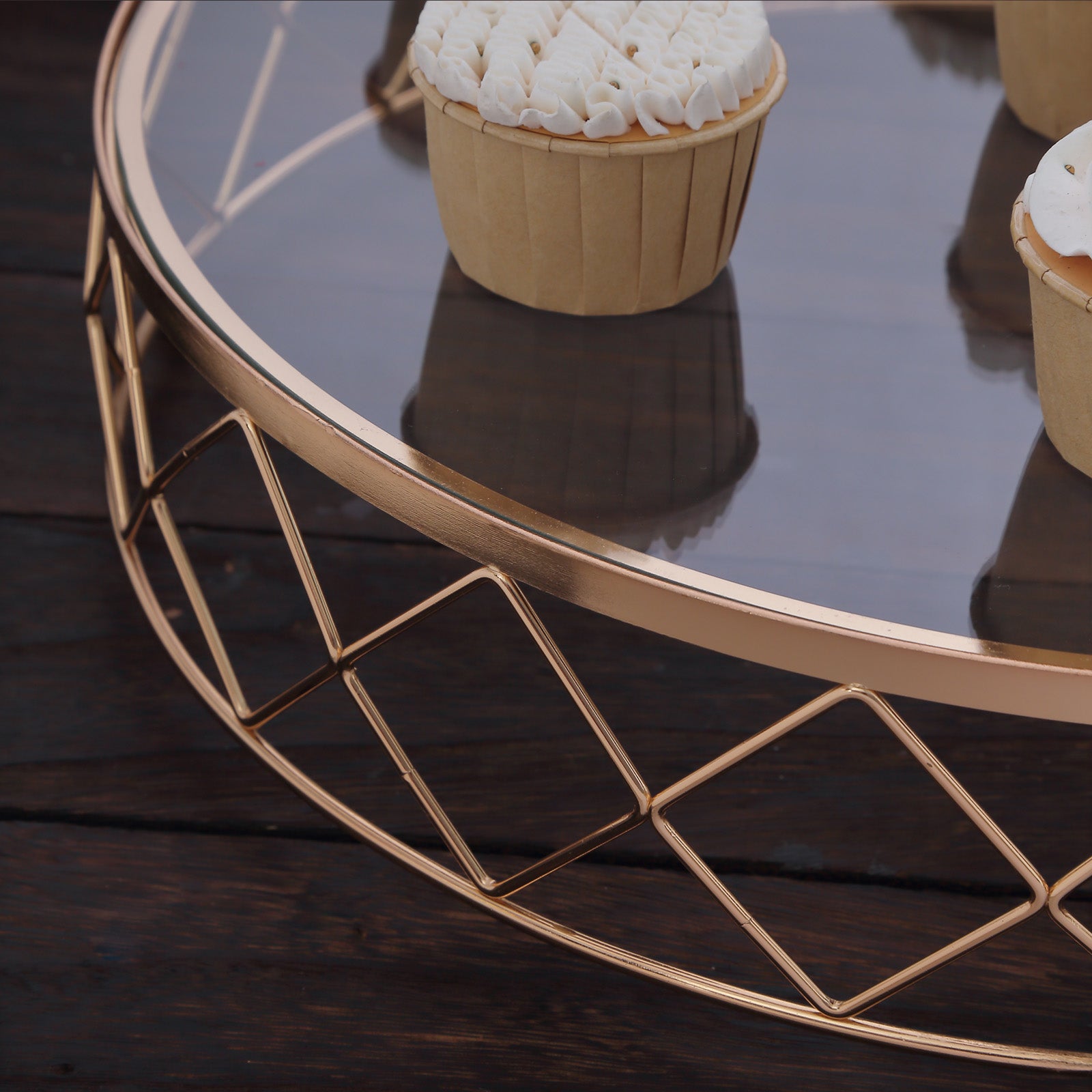 Gold metal geometric diamond cut cake stand with glass top and cupcakes.