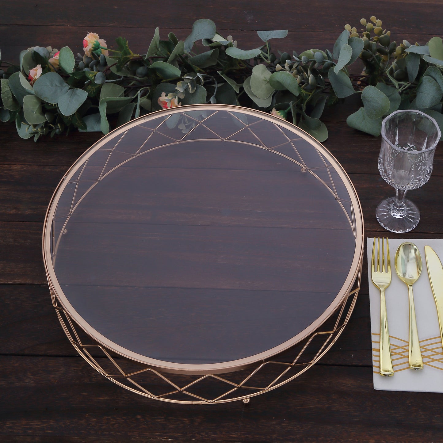 Gold geometric diamond cut cake stand with glass top on a wooden table.
