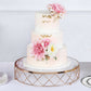 Gold geometric cake stand with glass top, featuring a three-tiered floral cake.