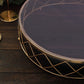 Gold geometric diamond cut cake stand with glass top on a wooden surface.