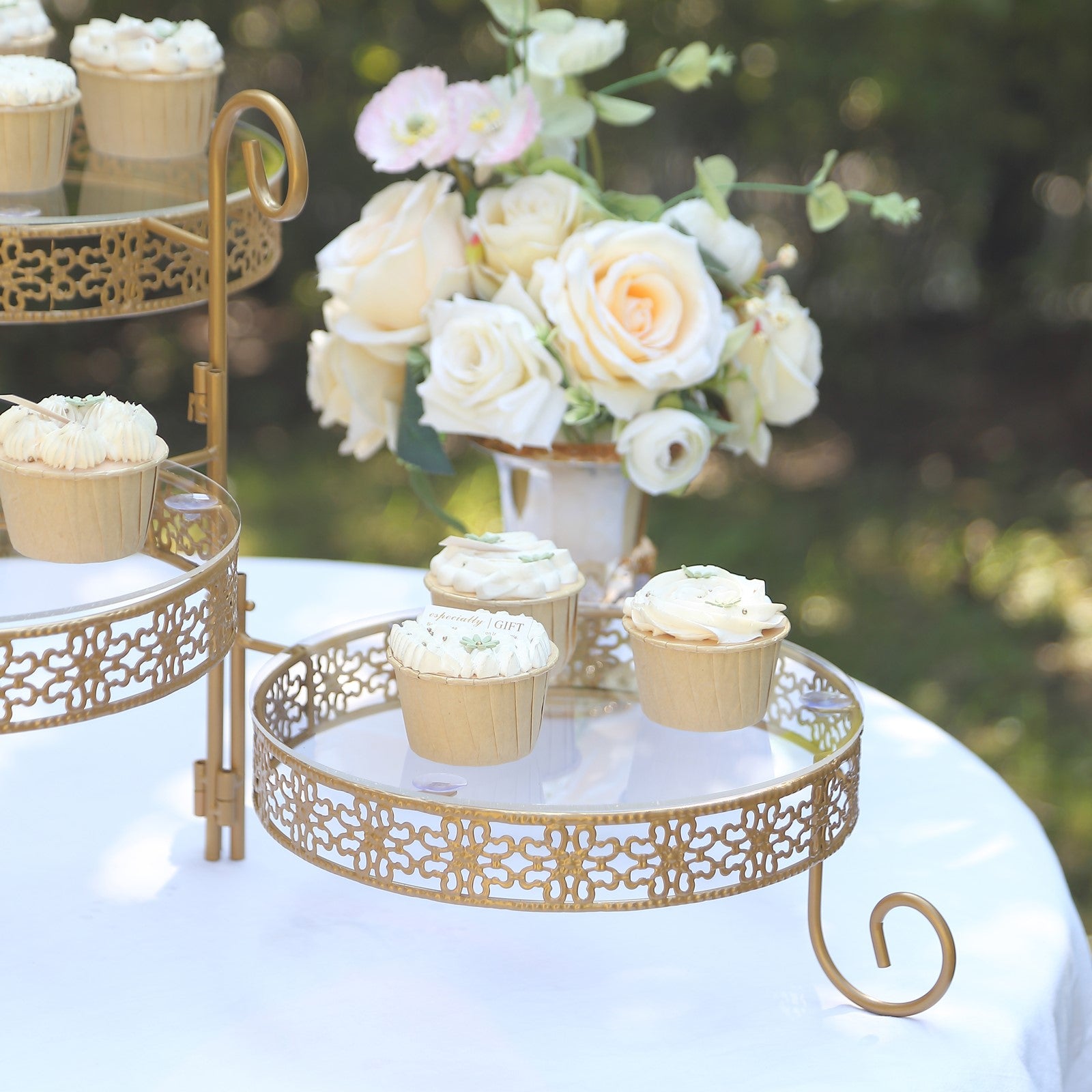Gold metal rotating cake stand with clear acrylic plates and cupcakes.