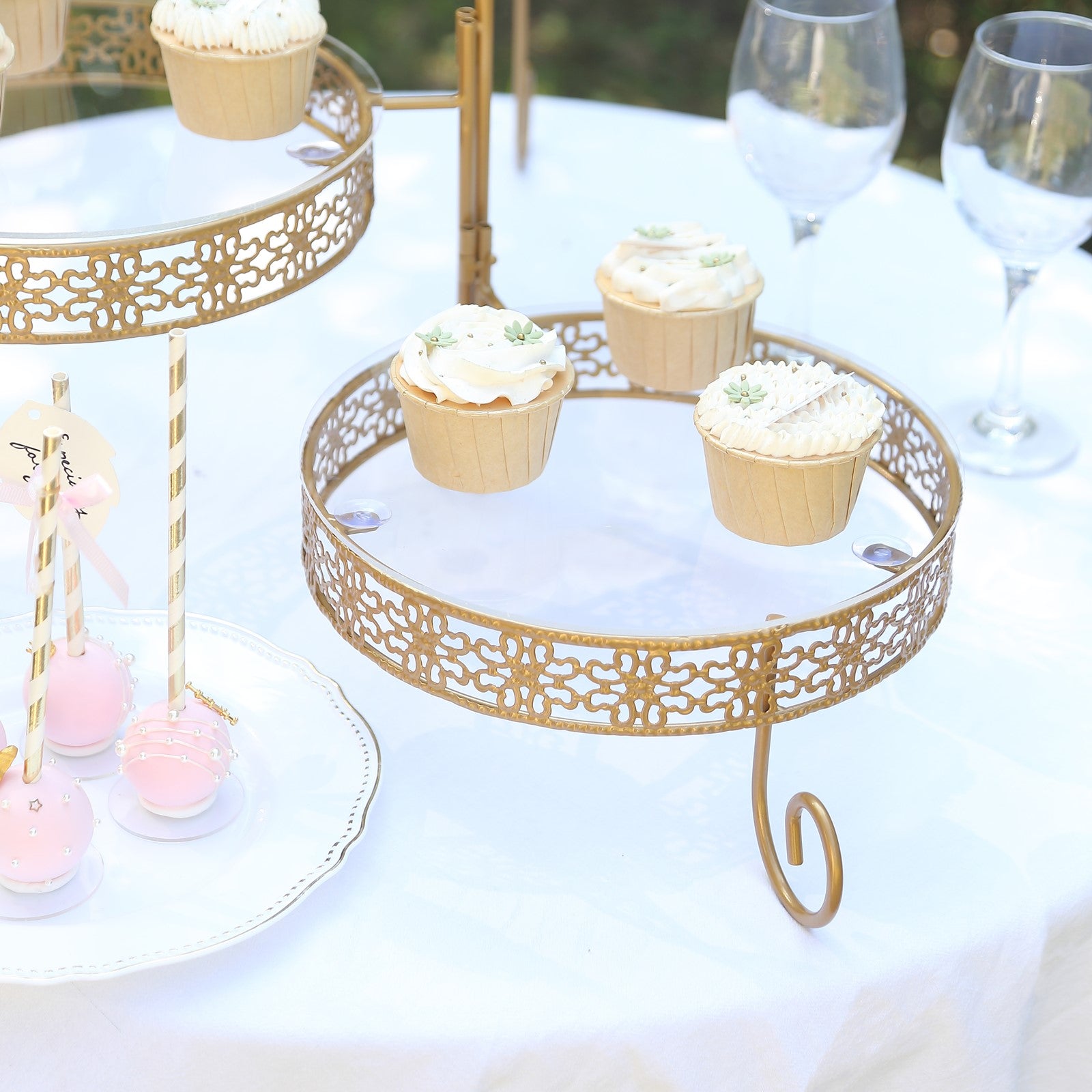 Gold rotating cake stand with clear acrylic plates and lace design, perfect for desserts.