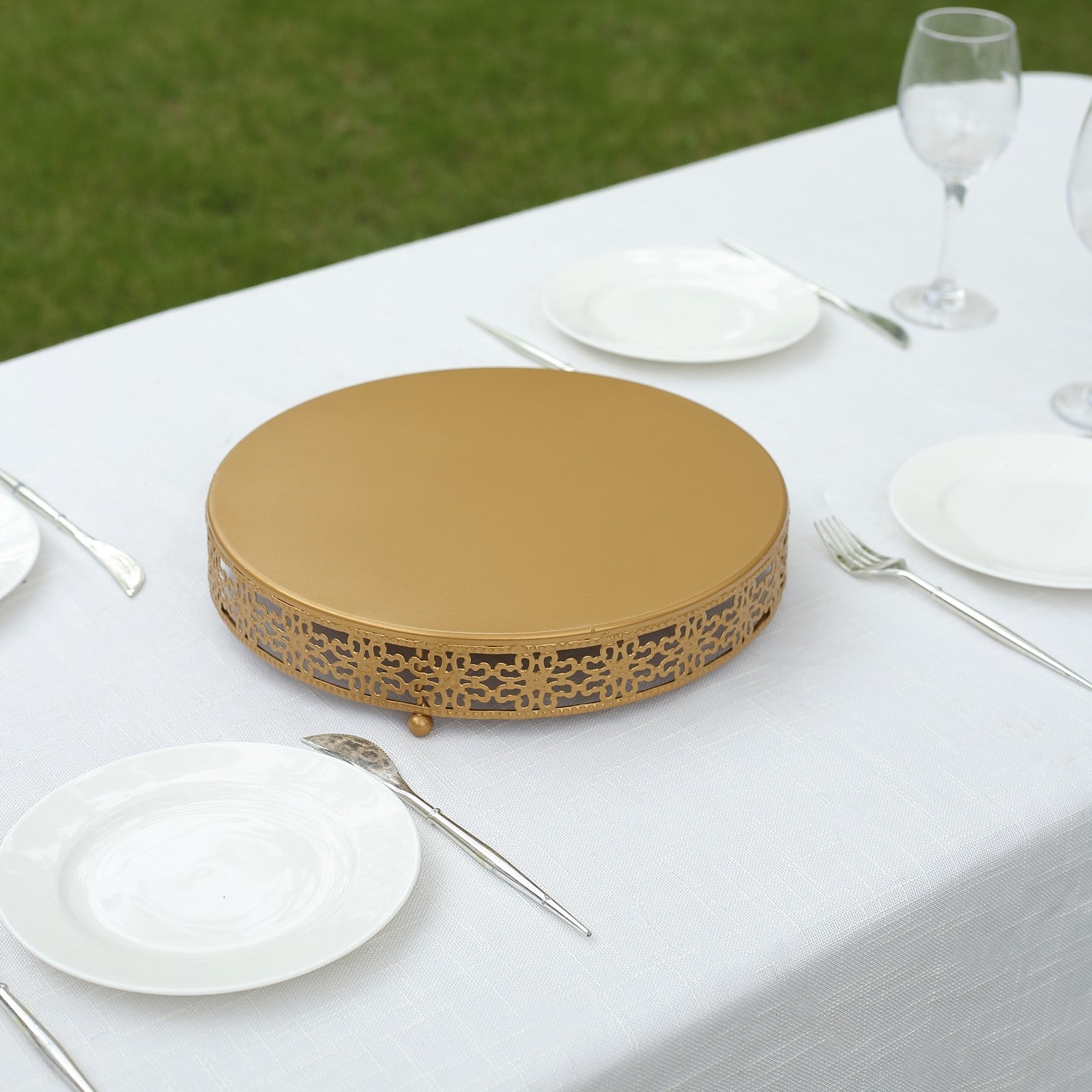 Gold metal cupcake display stand on a table with white plates.