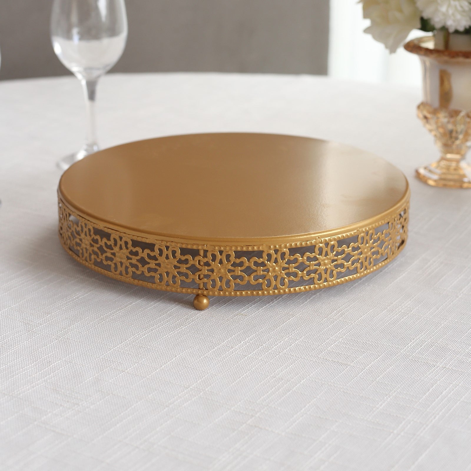 Gold metal fleur de lis cupcake display stand on a table.