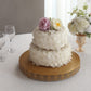 Gold metal fleur de lis cupcake stand with a two-tier cake and flowers.