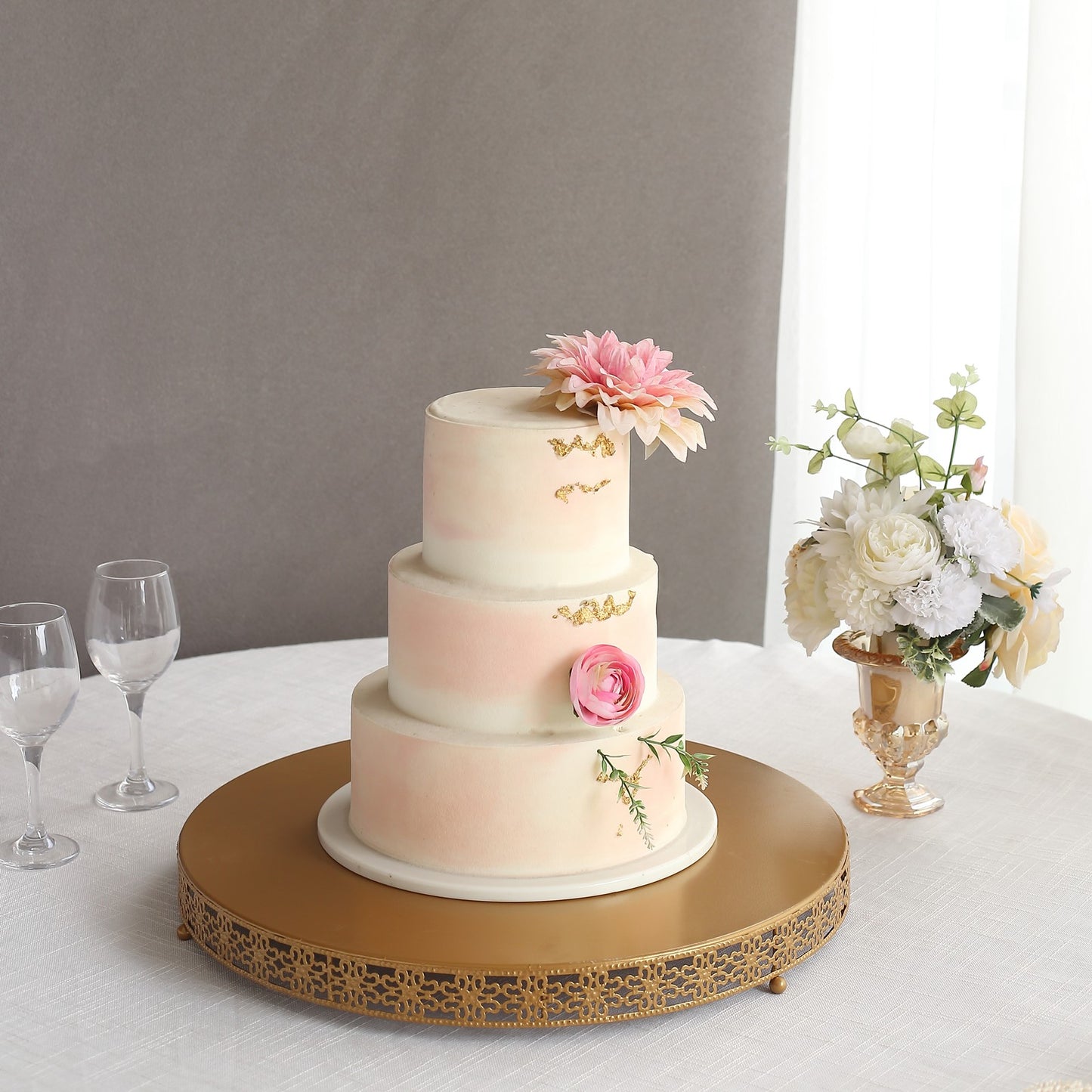 Gold metal round pedestal cake stand with a floral cake centerpiece.