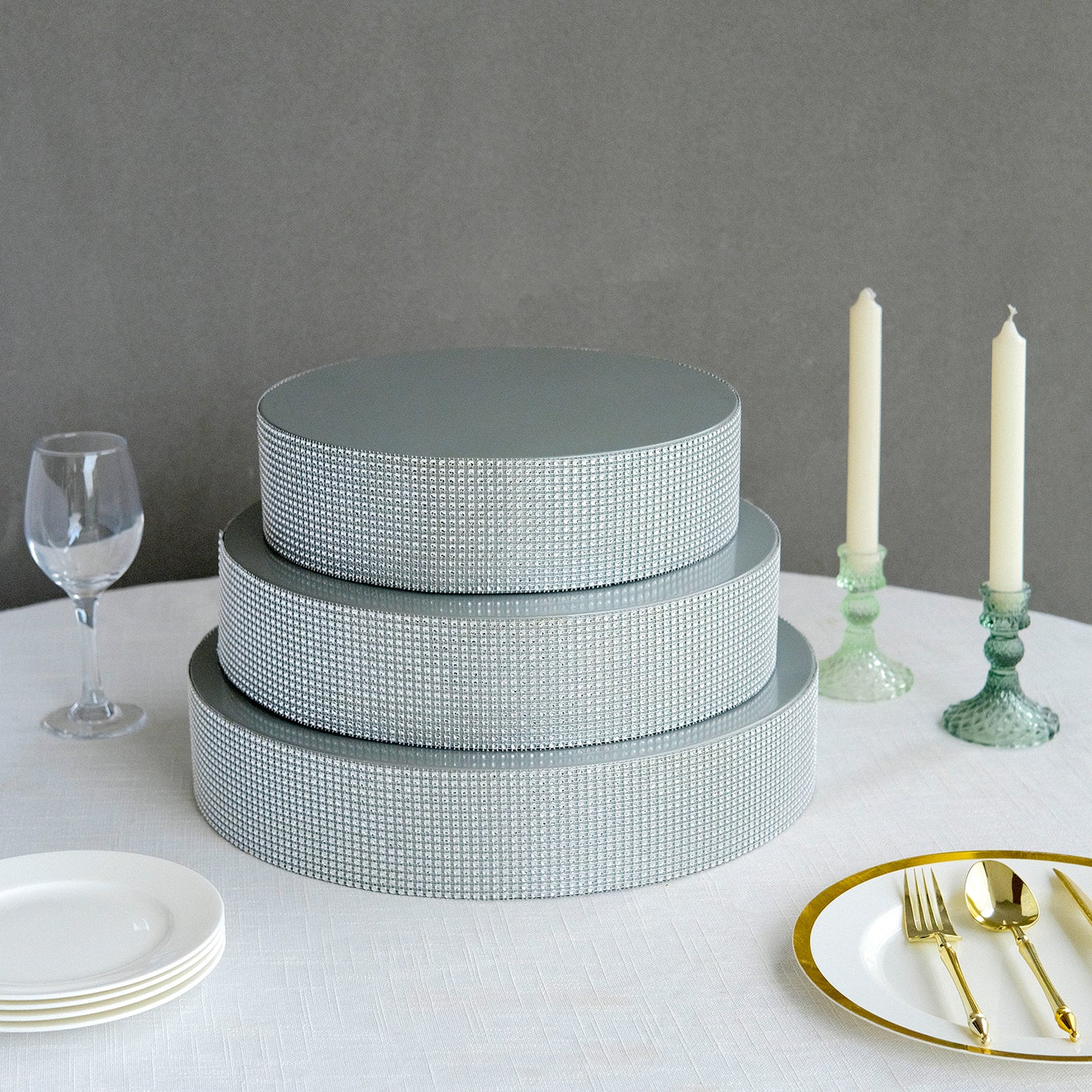 Silver rhinestone round metal cake stand on a table setting.