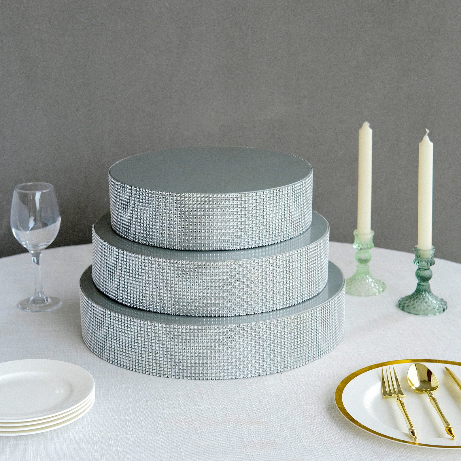 Silver rhinestone round metal cake stand on a table setting.