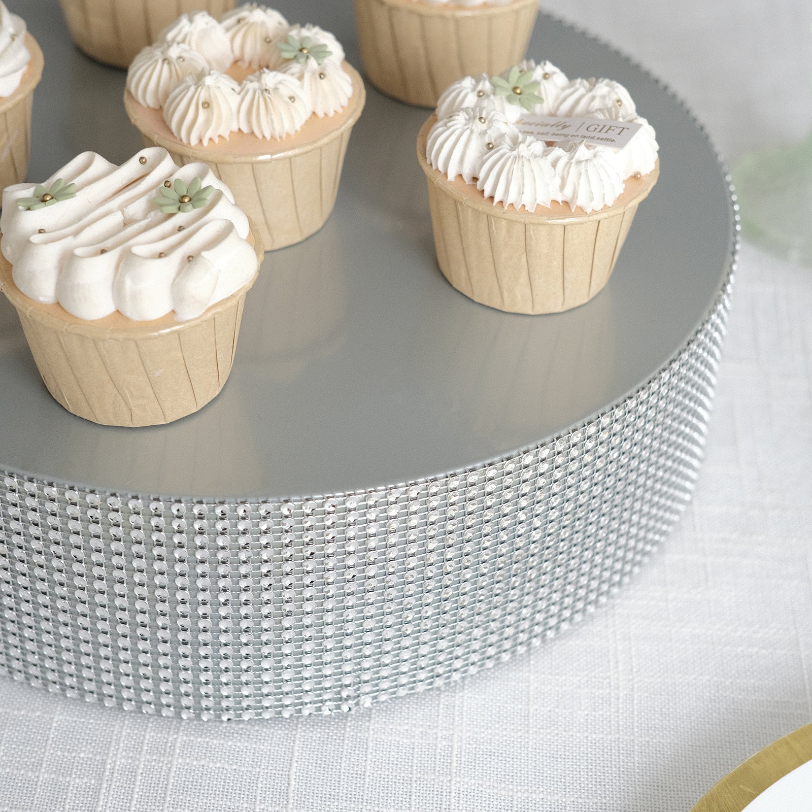 Silver rhinestone round metal cake stand with cupcakes on top.