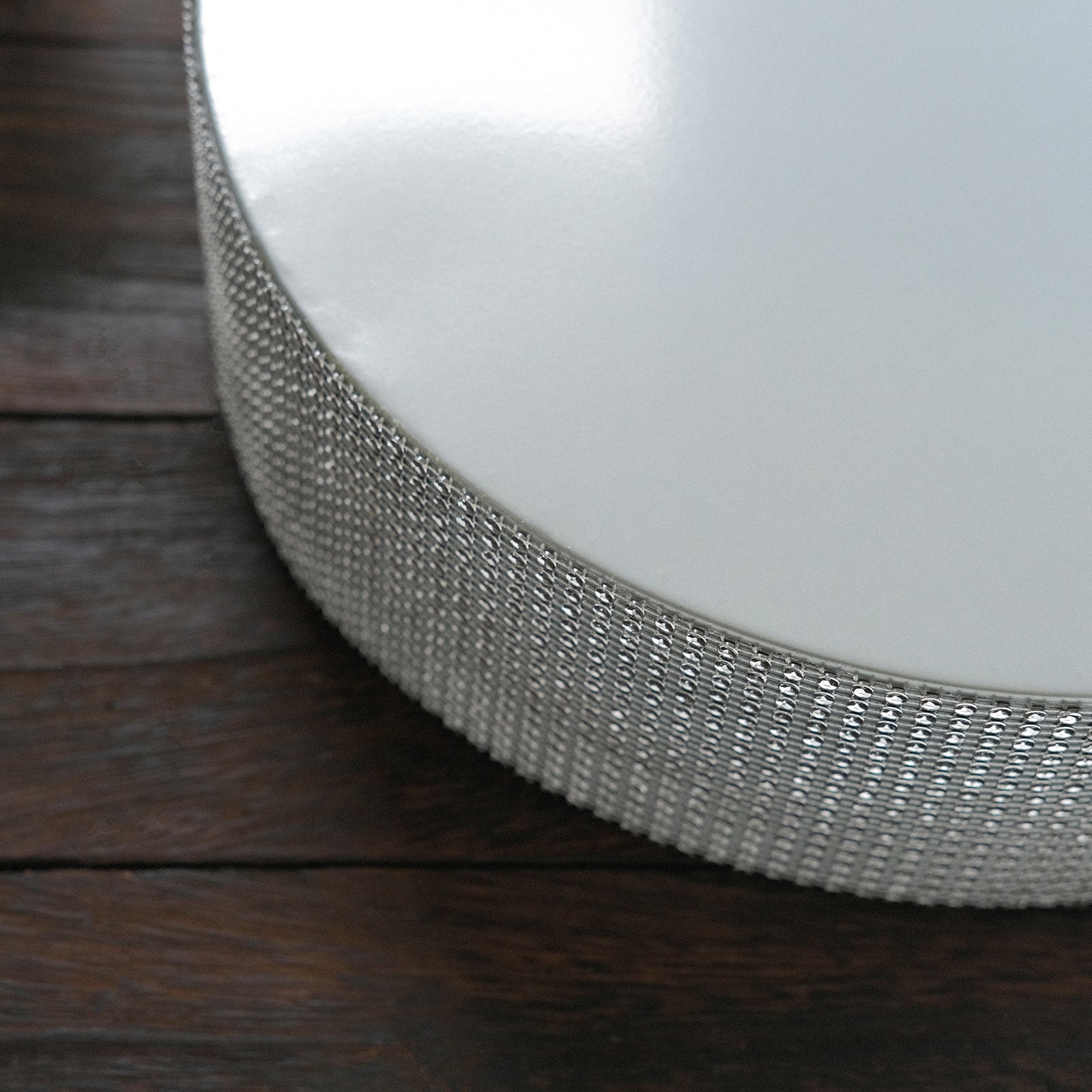 Silver rhinestone round metal cake stand on a wooden table.