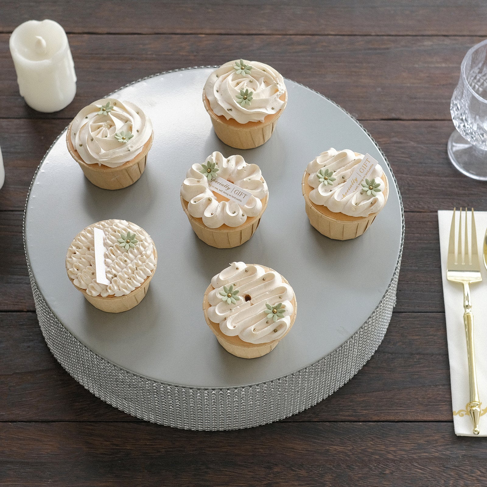 Silver round metal pedestal cake stand displaying cupcakes.